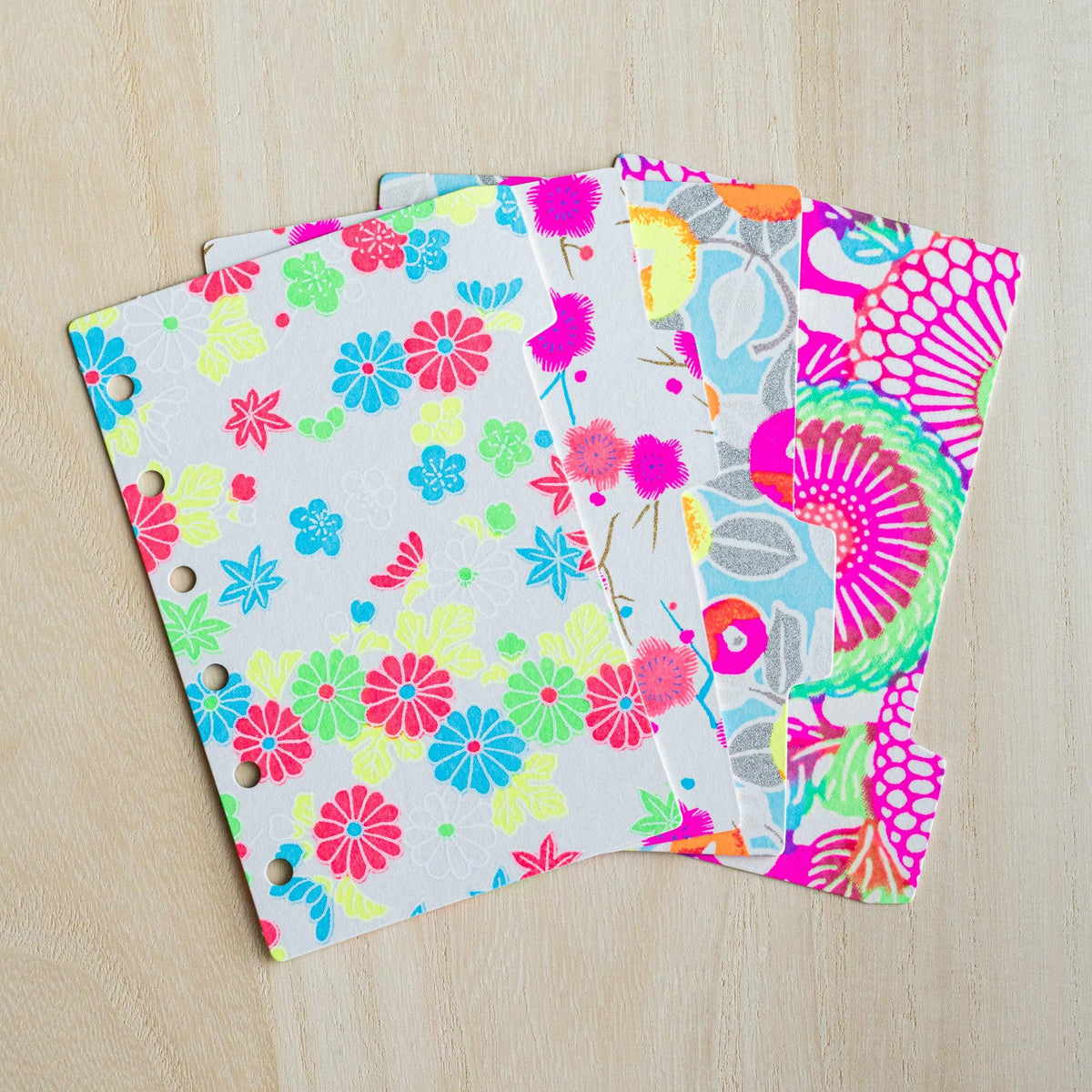 Four neon Yuzen washi index dividers for Mini 6 planners fanned out, showing staggered side tabs and six holes
