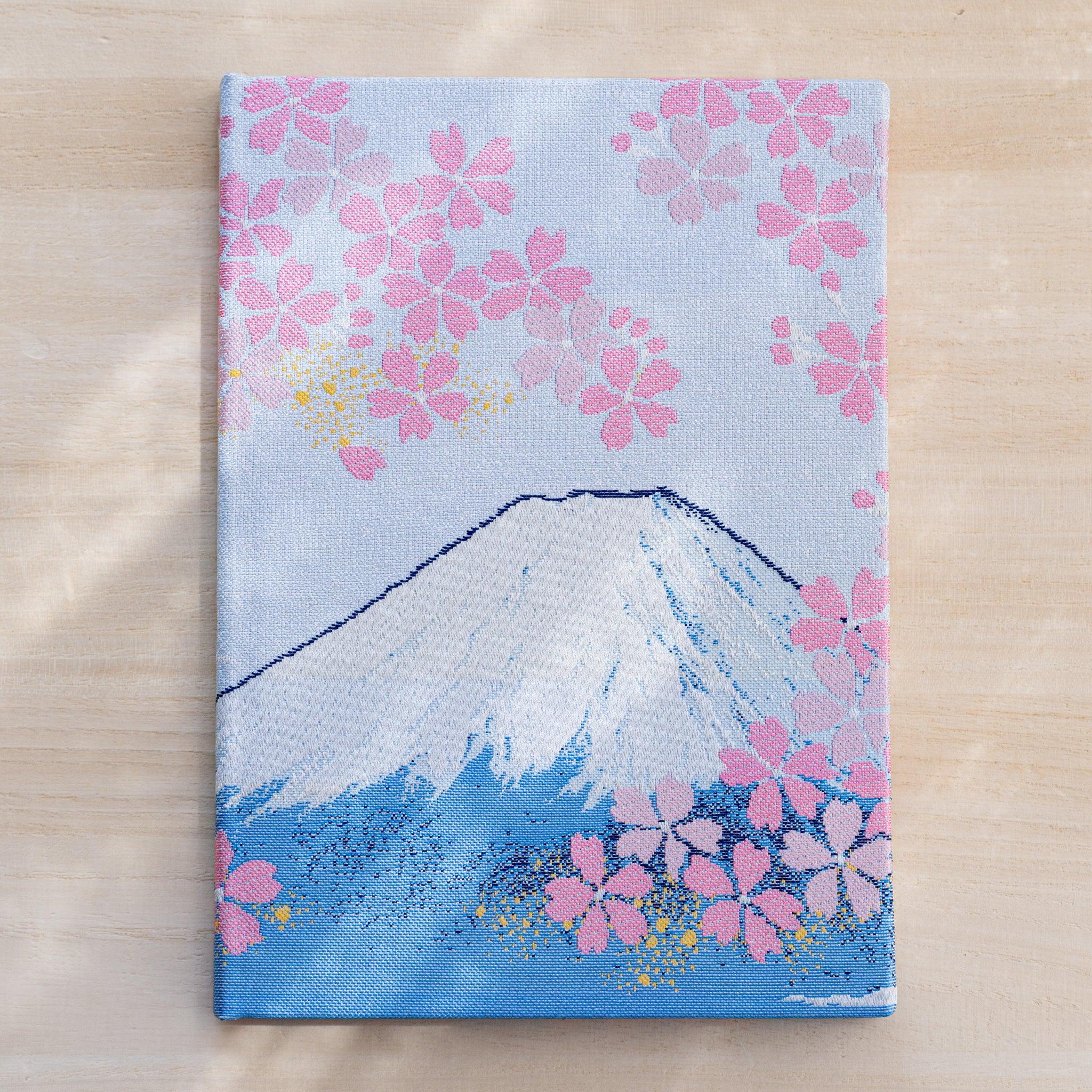Notebook front cover in woven Nishijin textile, white-capped Mount Fuji and pink cherry blossoms on pale blue ground
