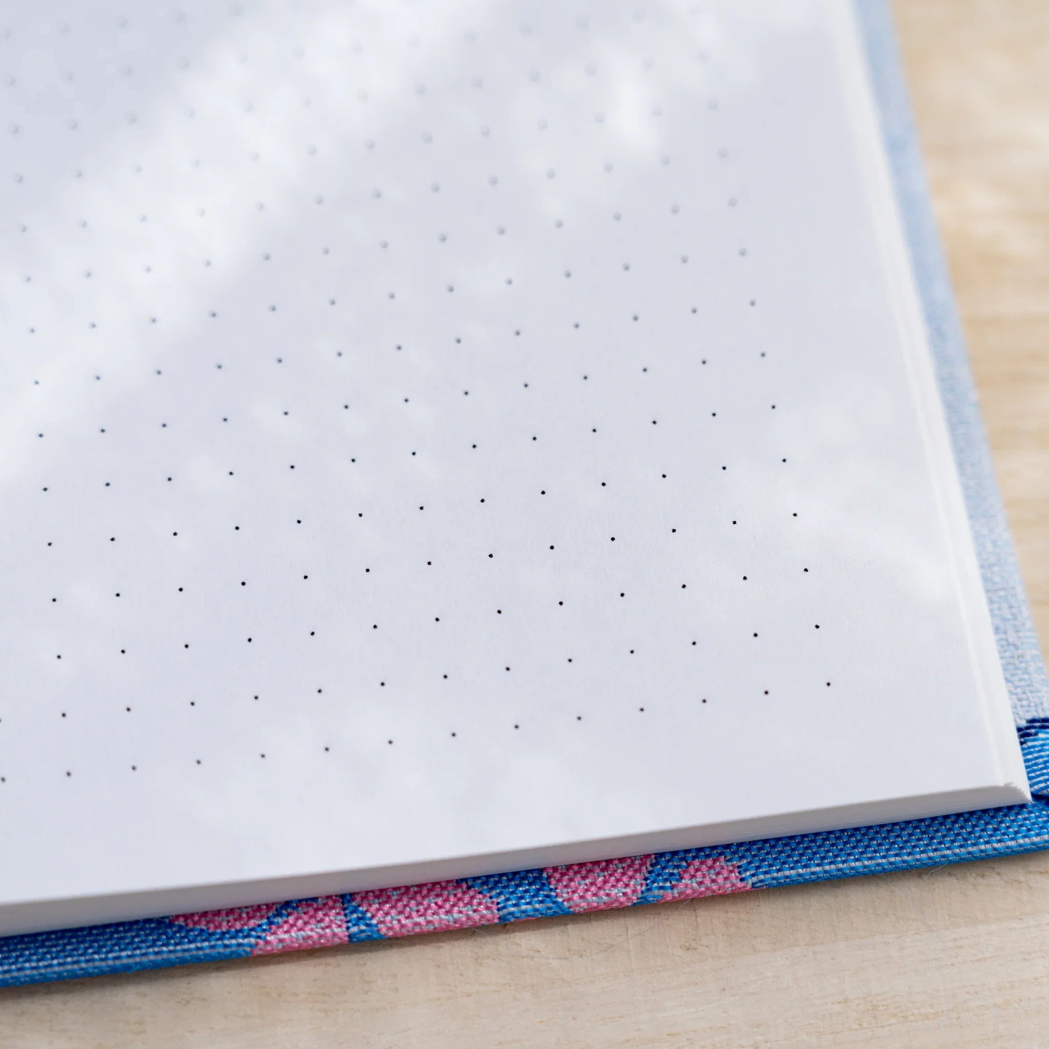 Close-up of a dot grid page corner with blue and pink woven textile hardcover edge