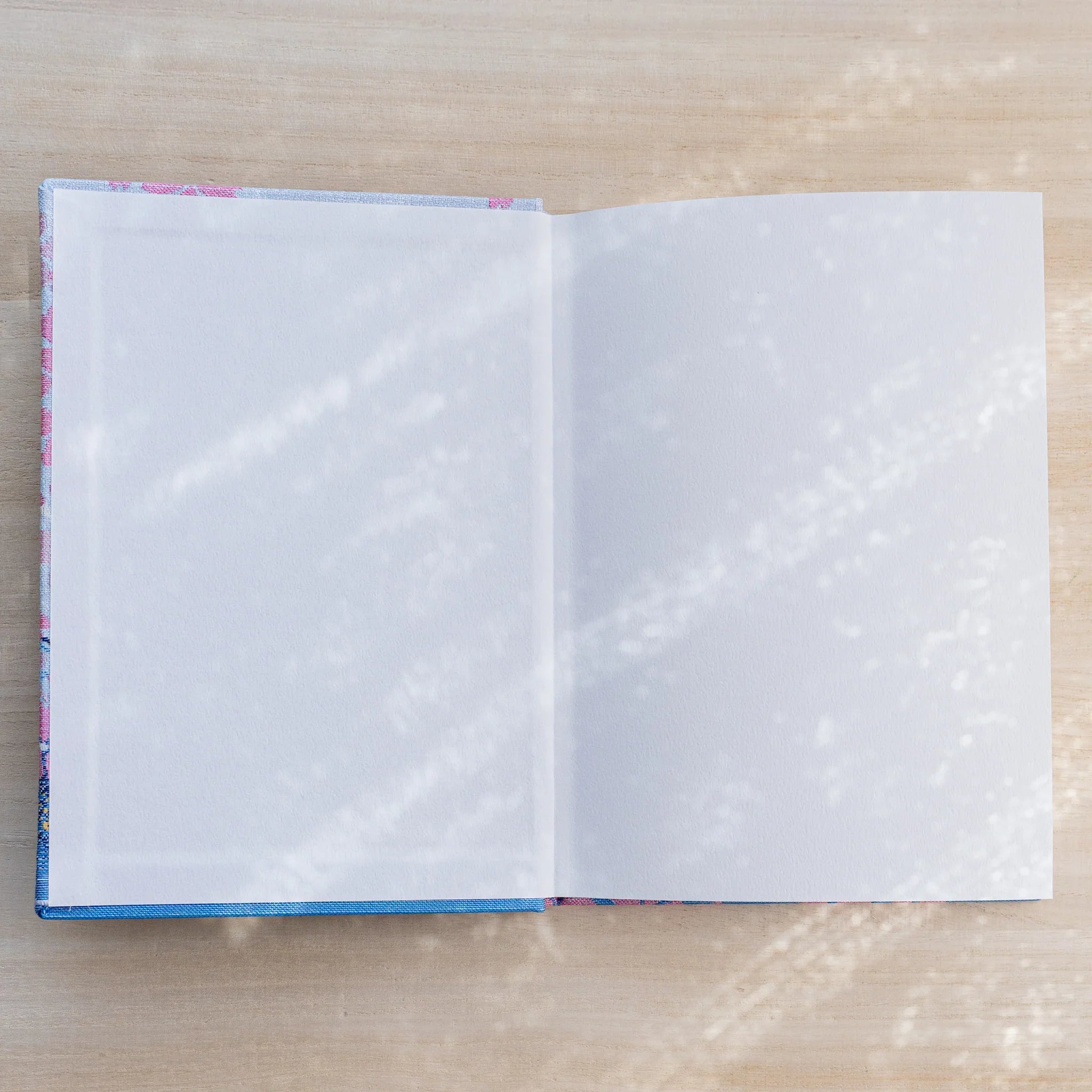 Notebook opened flat to two blank white pages, woven textile inner cover visible at the edges