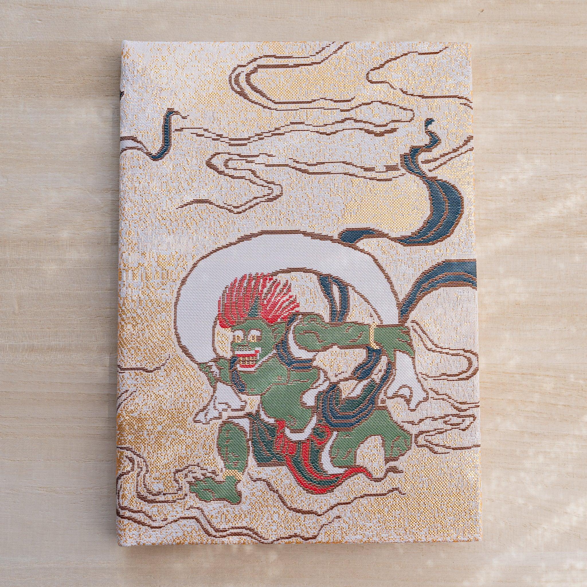 Notebook front cover in woven Nishijin textile showing green wind god Fujin with a wind bag on a gold cloud ground