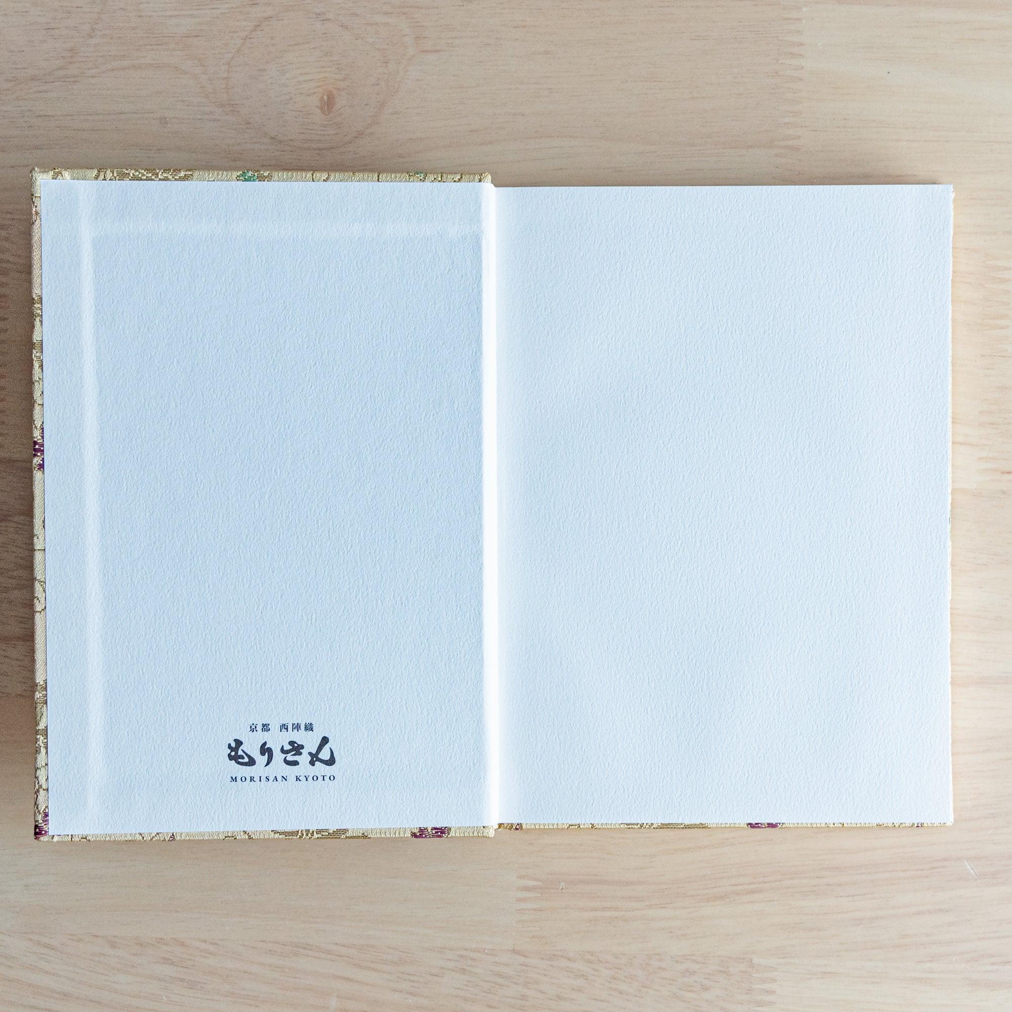 An open Japanese notebook showing white pages with a subtle dot grid pattern, ideal for writing or sketching.