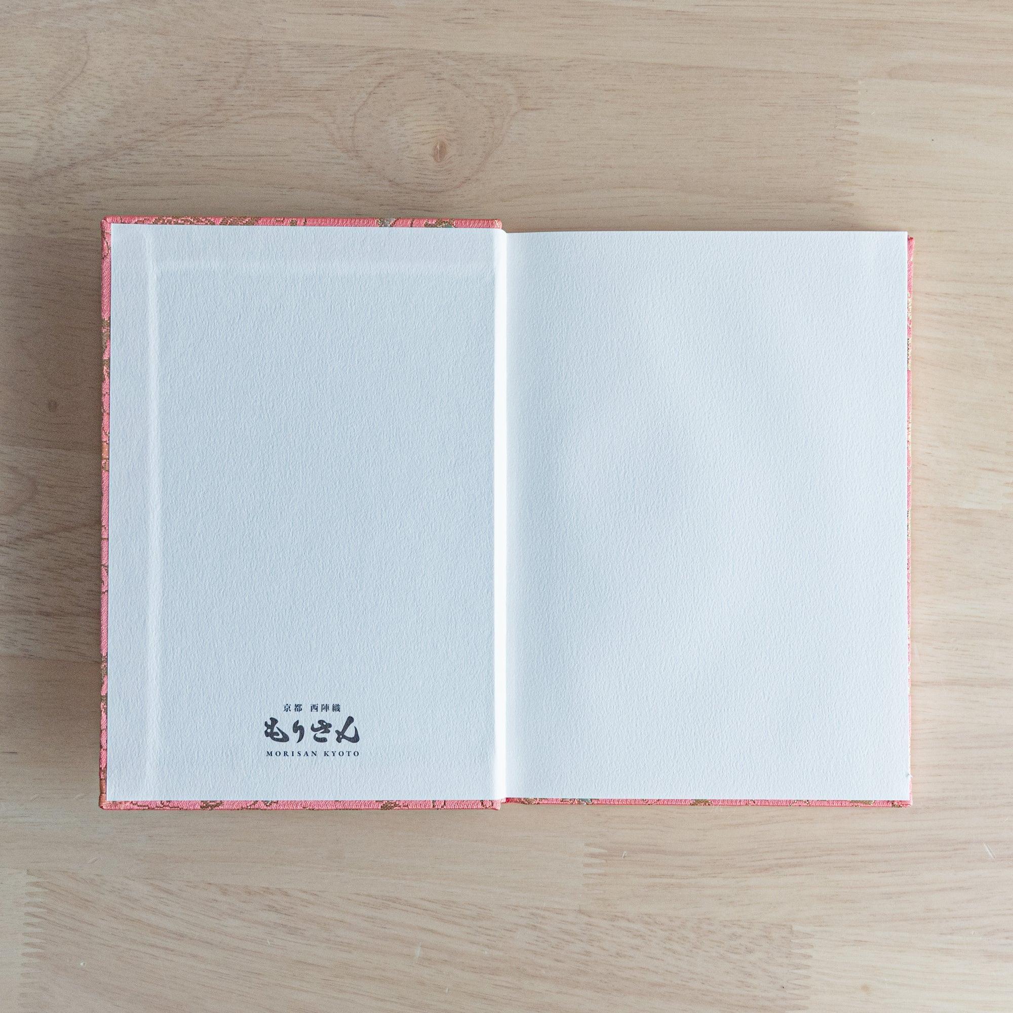 An open Japanese notebook showing white pages with a subtle dot grid pattern, ideal for writing or sketching.