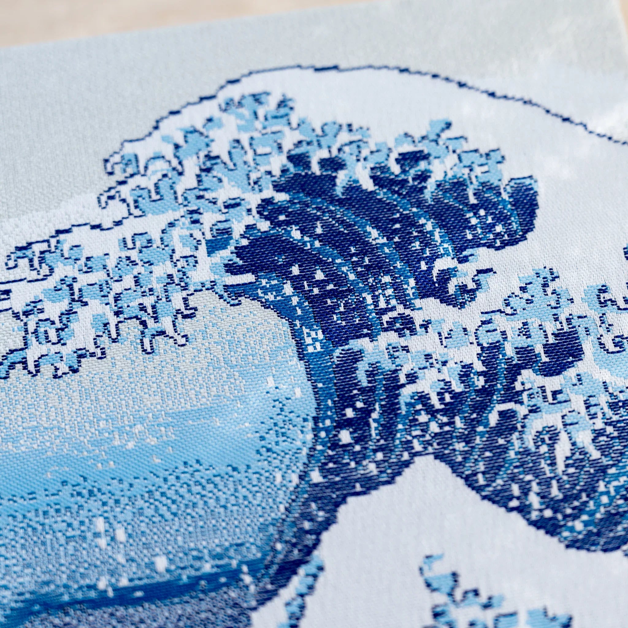 Close-up of woven textile showing the cresting blue and white foam of the Great Wave