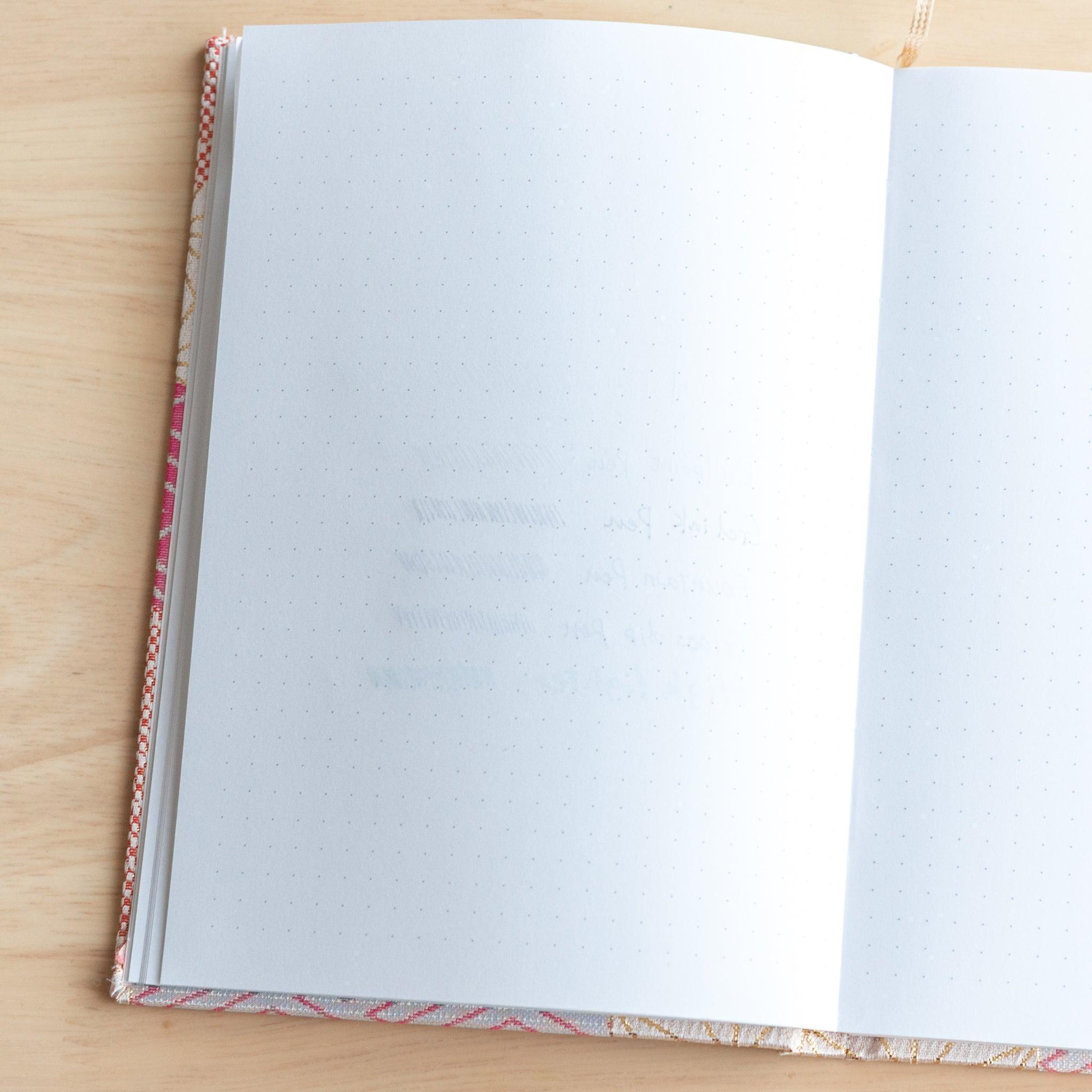 The next notebook page shows slight ink ghosting from the previous writing, with faint lines and text visible through the paper.