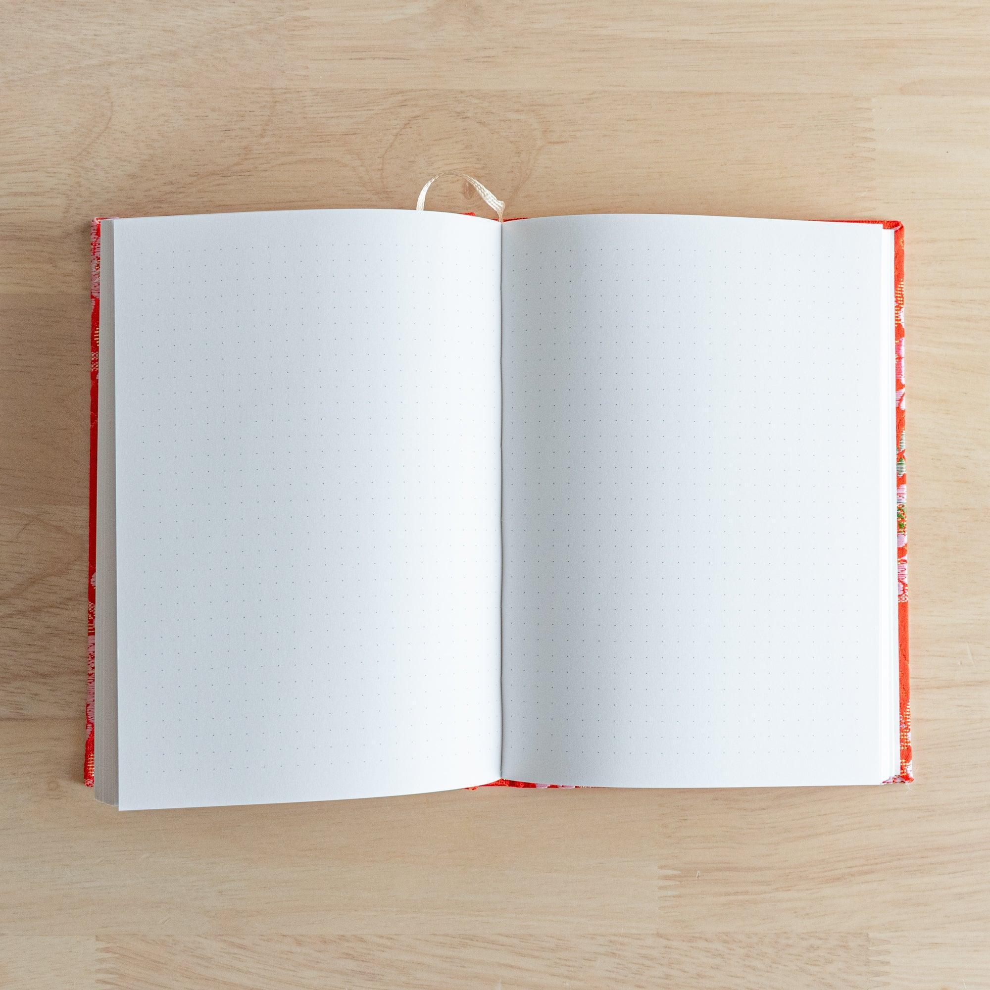 An open Japanese notebook showing white pages with a subtle dot grid pattern, ideal for writing or sketching.
