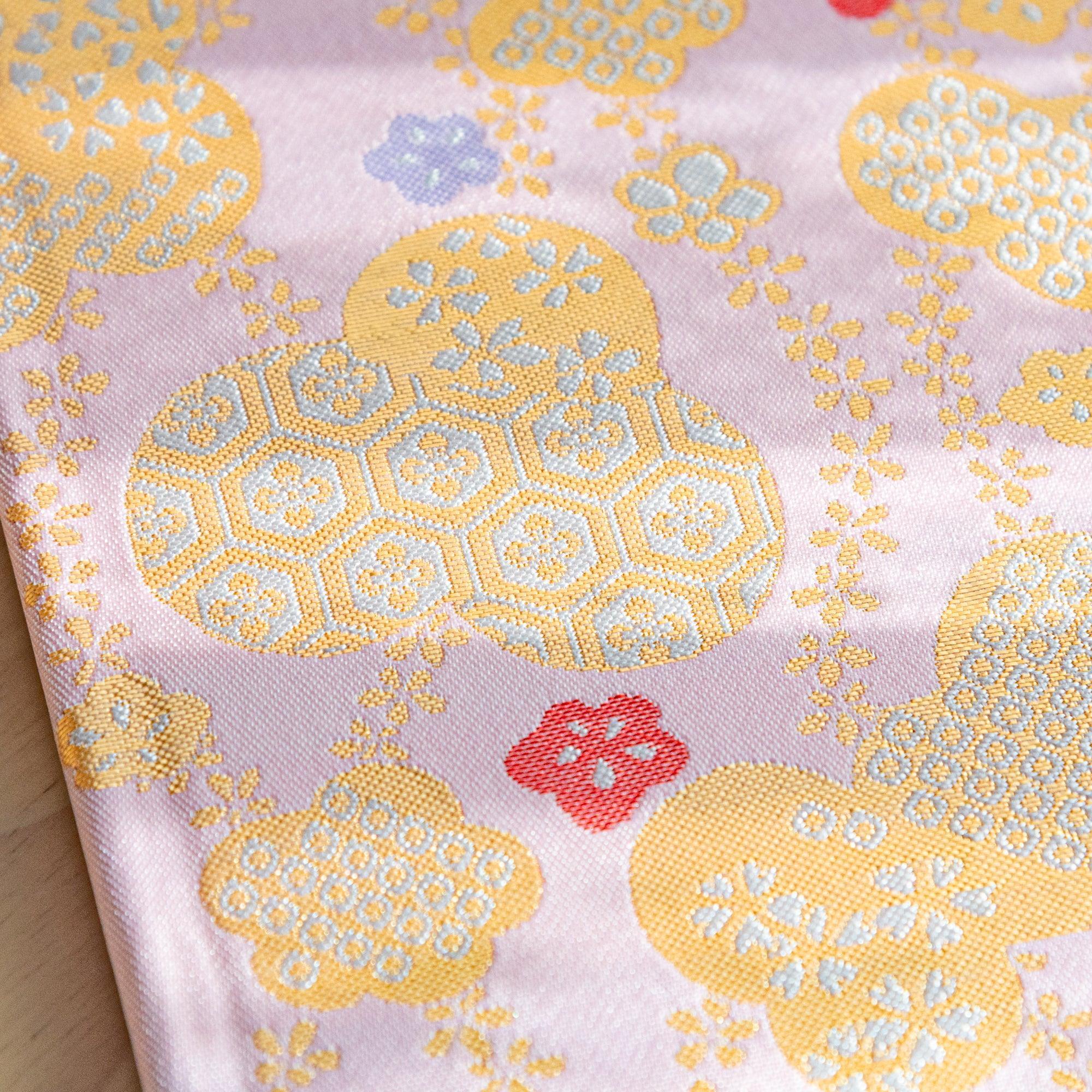 Another close-up of the fabric cover showcasing gold and pastel cloud motifs with red and green floral accents.