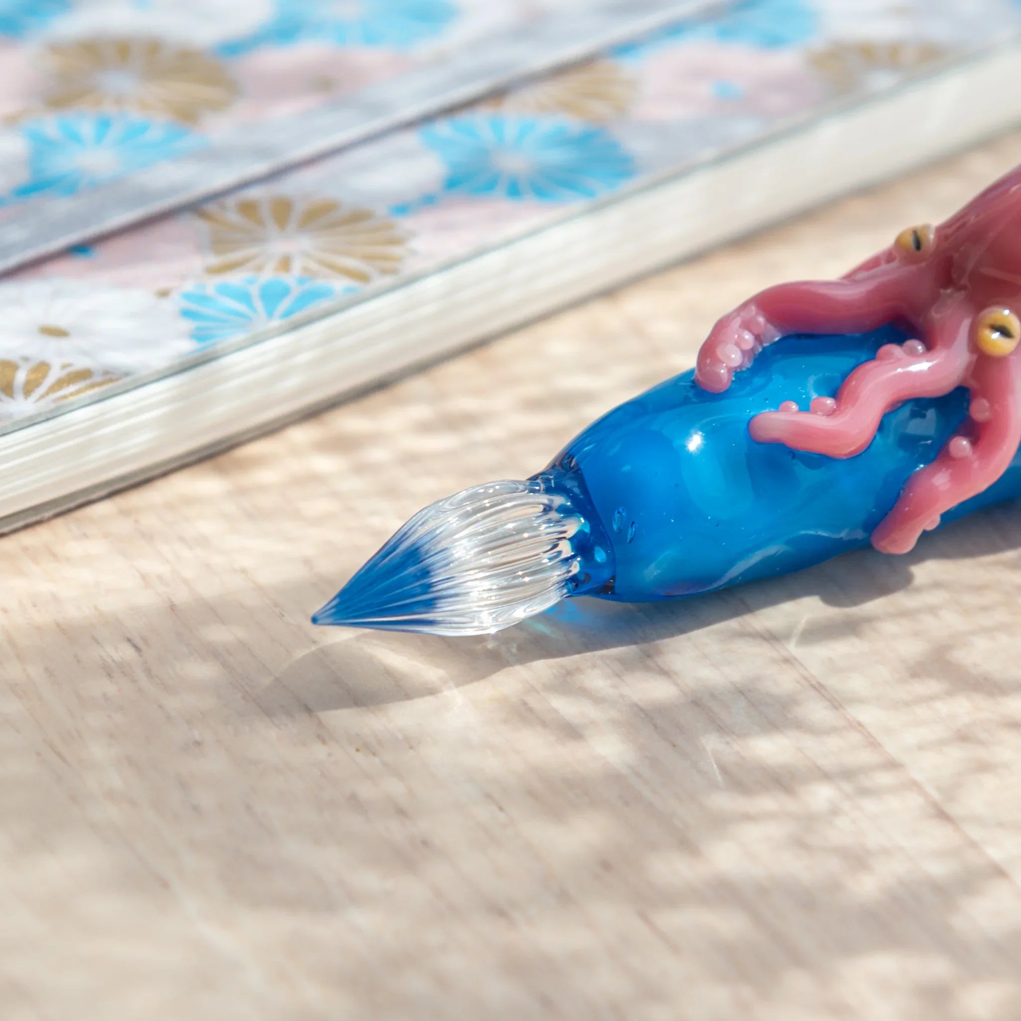Close-up of clear glass spiral nib on a Japanese glass dip pen with blue barrel and pink octopus tentacles visible