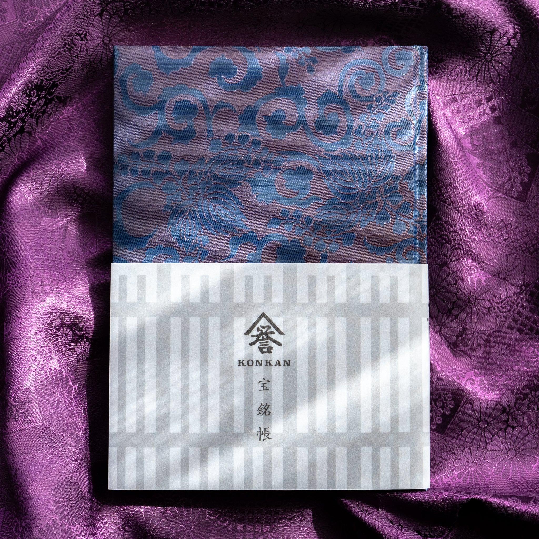 Oni Kiri Nishijin silk Homeicho notebook with KONKAN Ho Mei Cho Japanese paper band on purple patterned fabric background