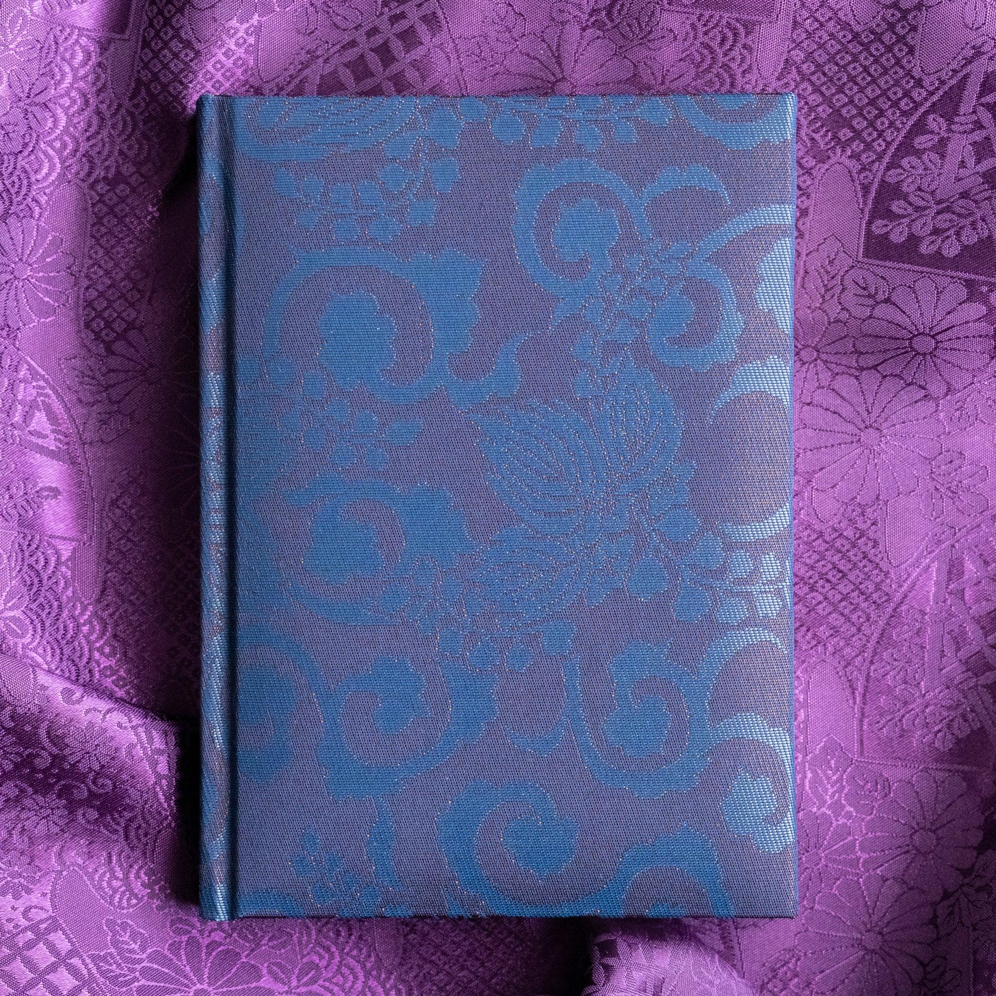 Oni Kiri Nishijin silk Homeicho notebook straight-on front cover showing blue Oni Kiri scroll pattern on purple fabric