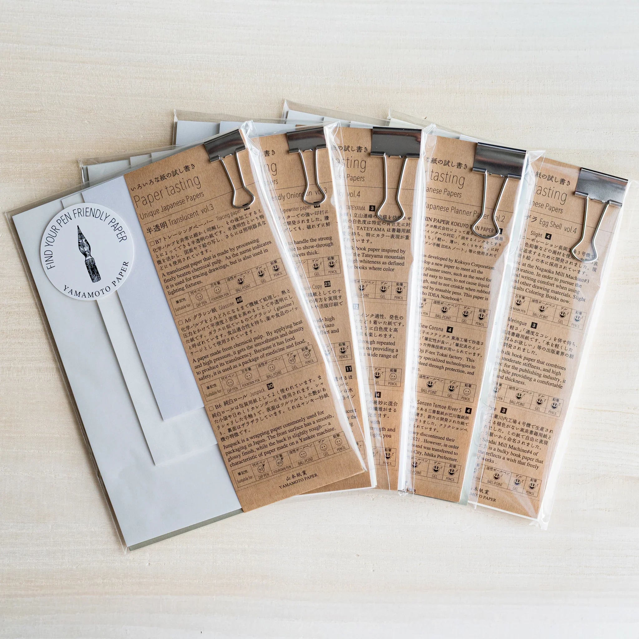 Five Yamamoto Paper Paper tasting writing pad sets fanned out in plastic sleeves, kraft covers, binder clips, nib sticker
