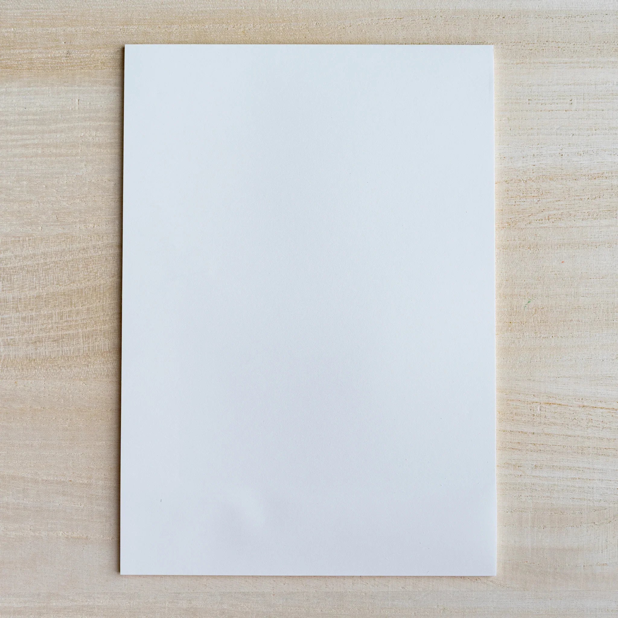 Blank white sheet of writing paper laid flat on light wood surface