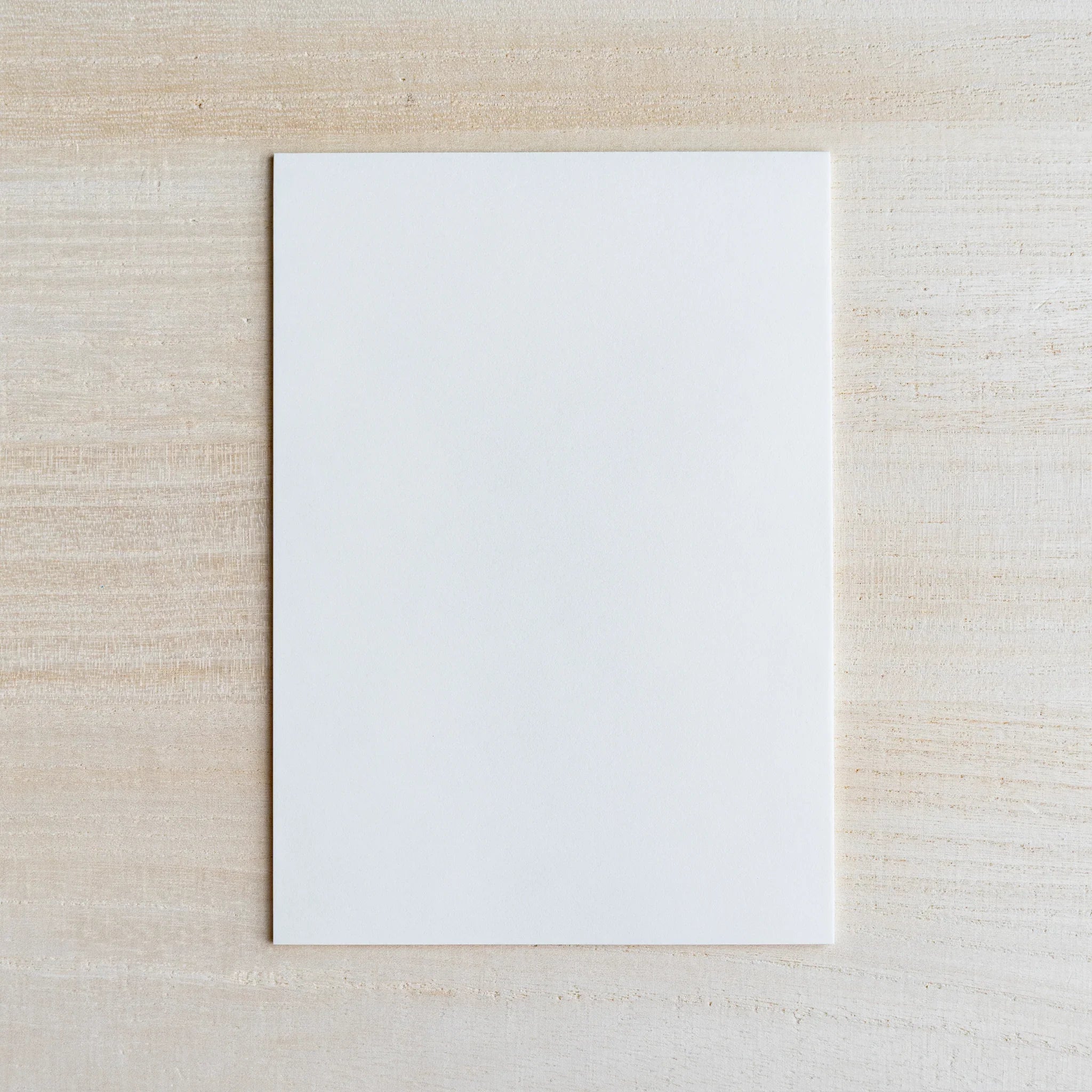 Single thin white onionskin writing sheet laid flat on light wood surface