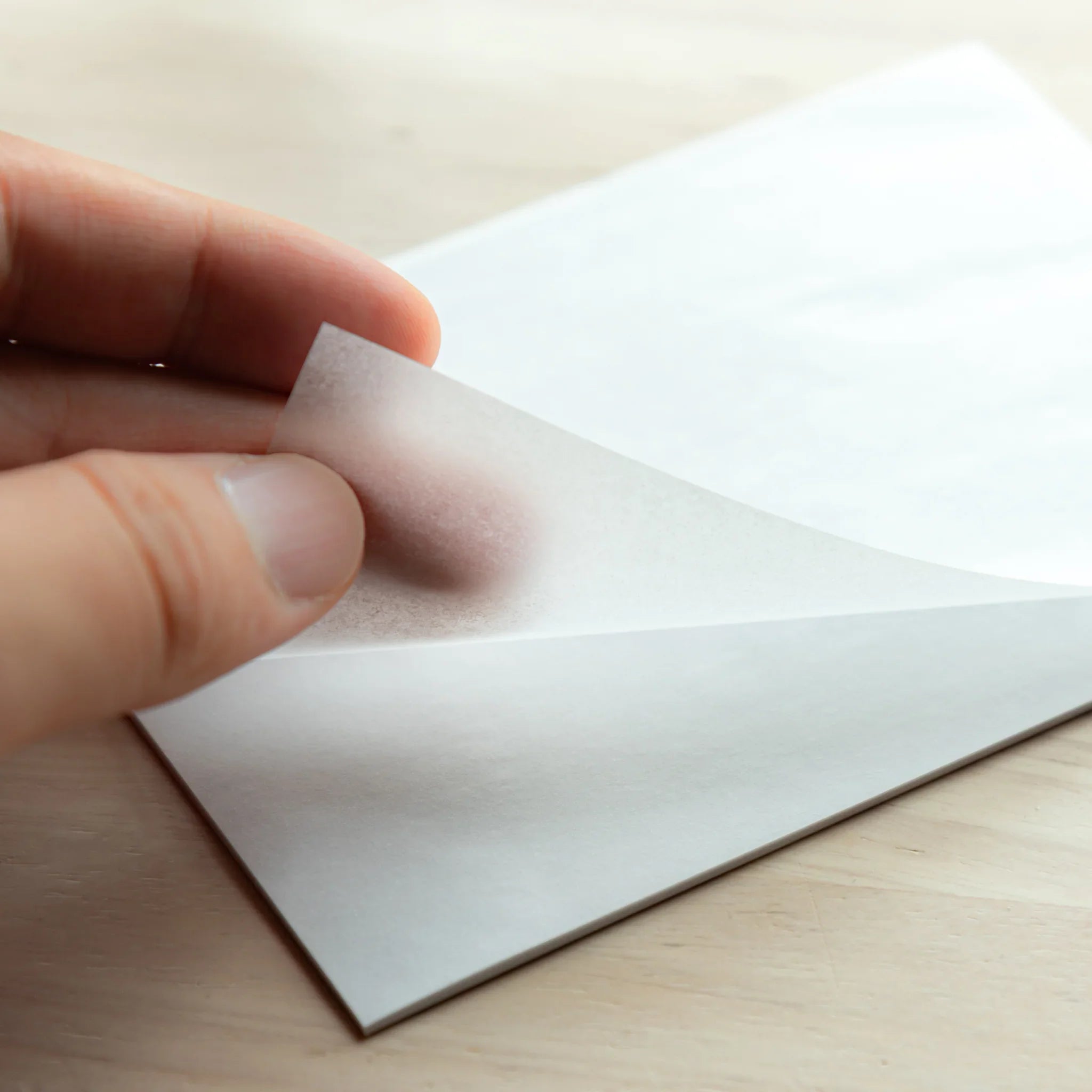 Hand flipping page of Paper Tasting Writing Pad Set, showing smooth Japanese Writing Pad sheets in clear texture.