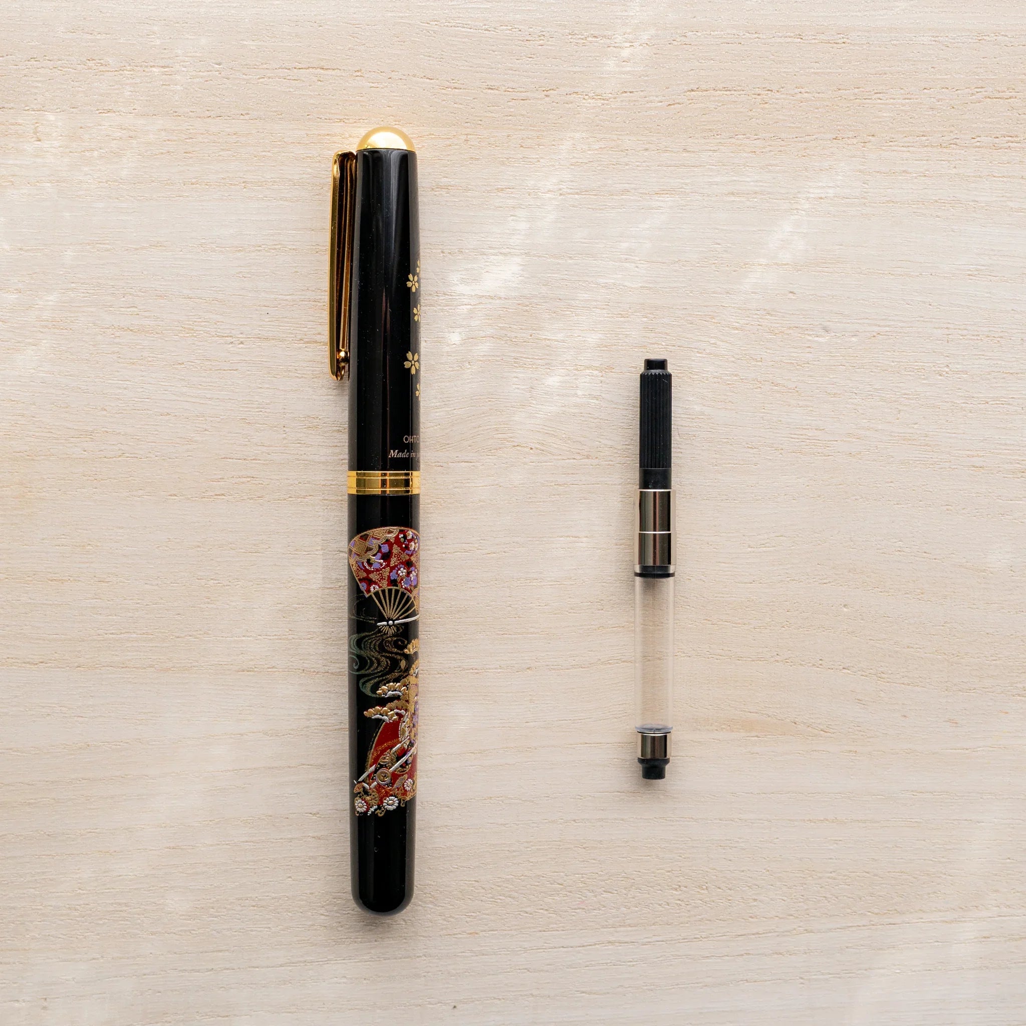 Yamanaka Japanese fountain pen with maki-e lacquer design alongside a Pelikan piston converter.