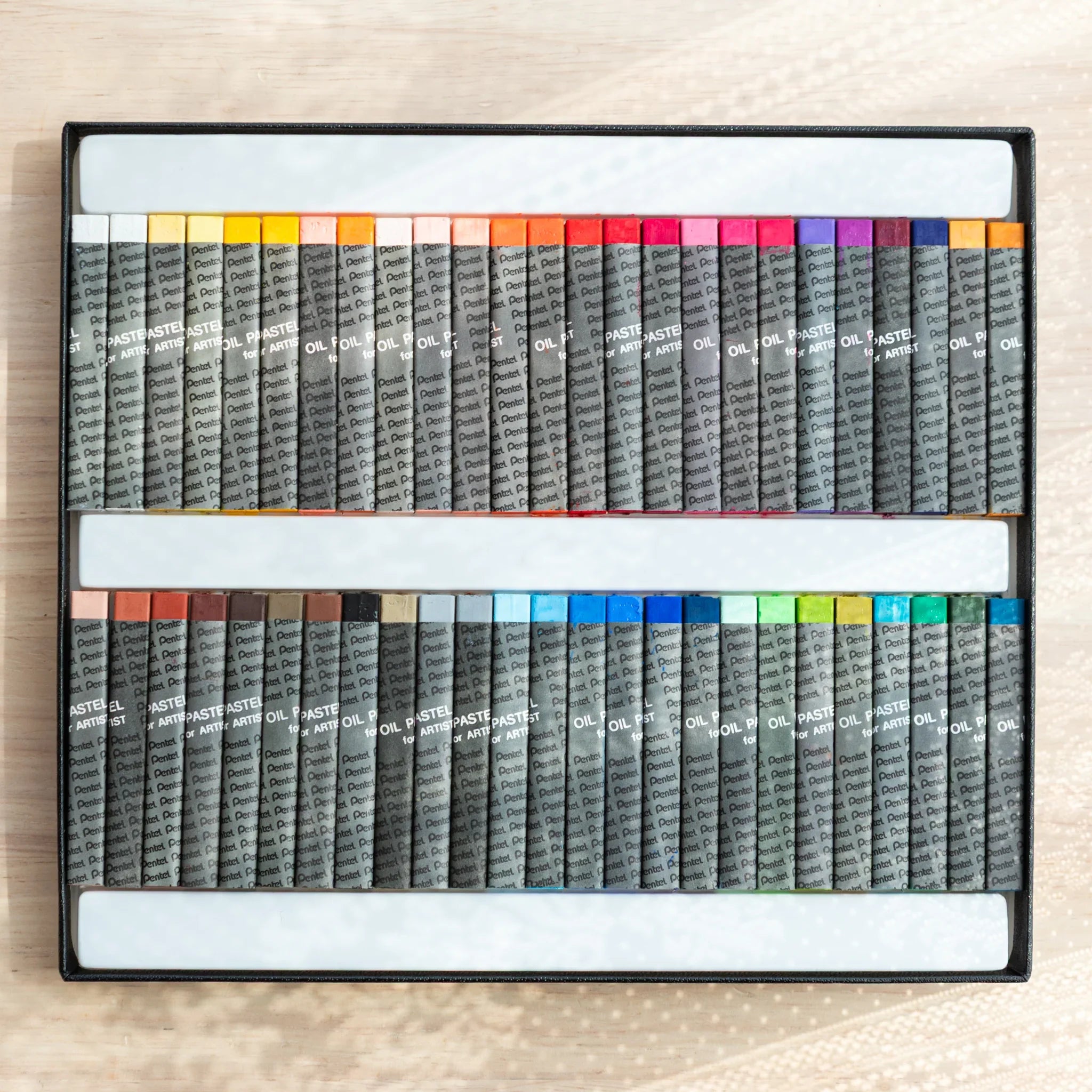 Open Pentel Oil Pastel for Artist box showing all 49 color sticks in two rows, warm tones in top row and cool tones in bottom