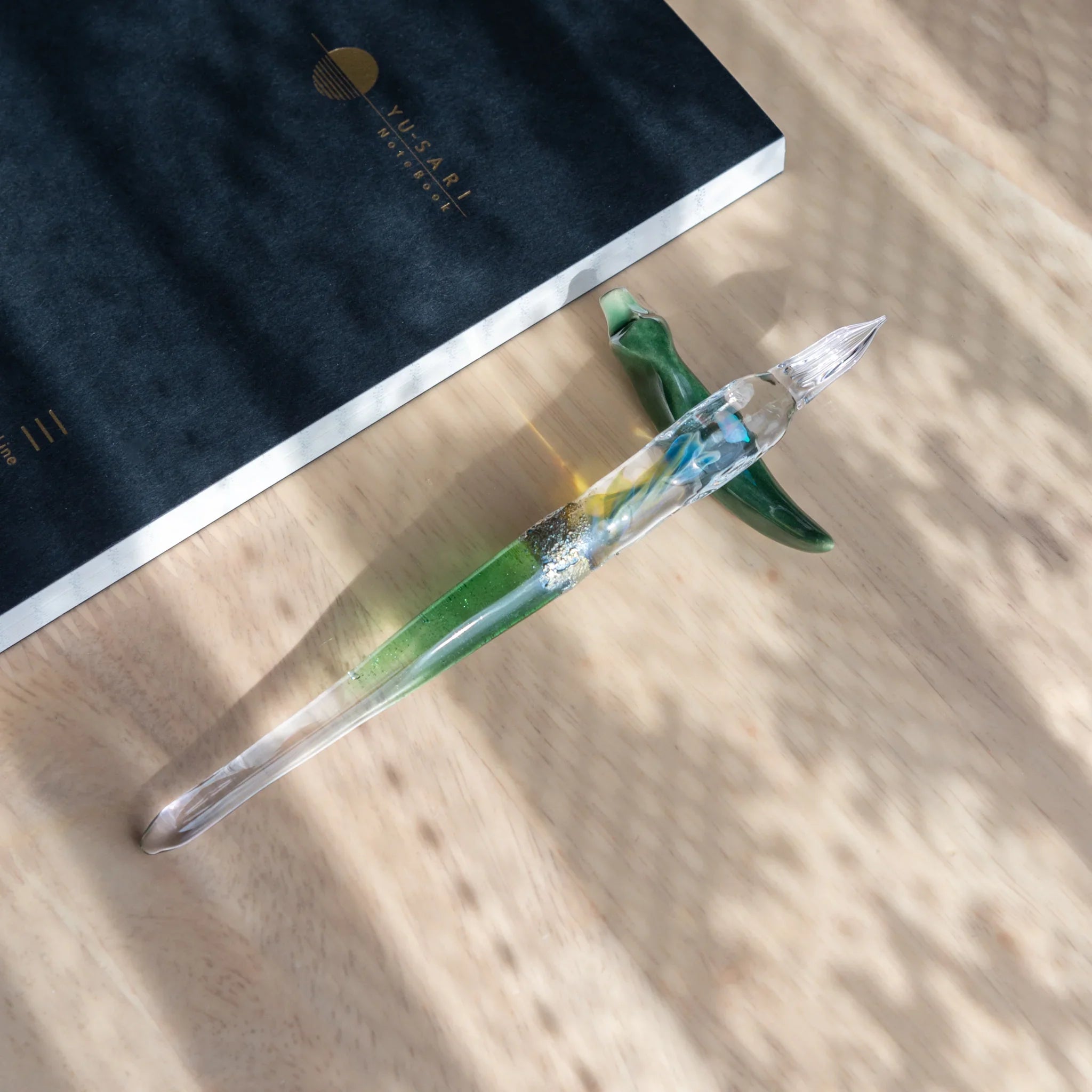 Flat lay composition of dark fountain pen with gold flower details positioned on black and gold background square