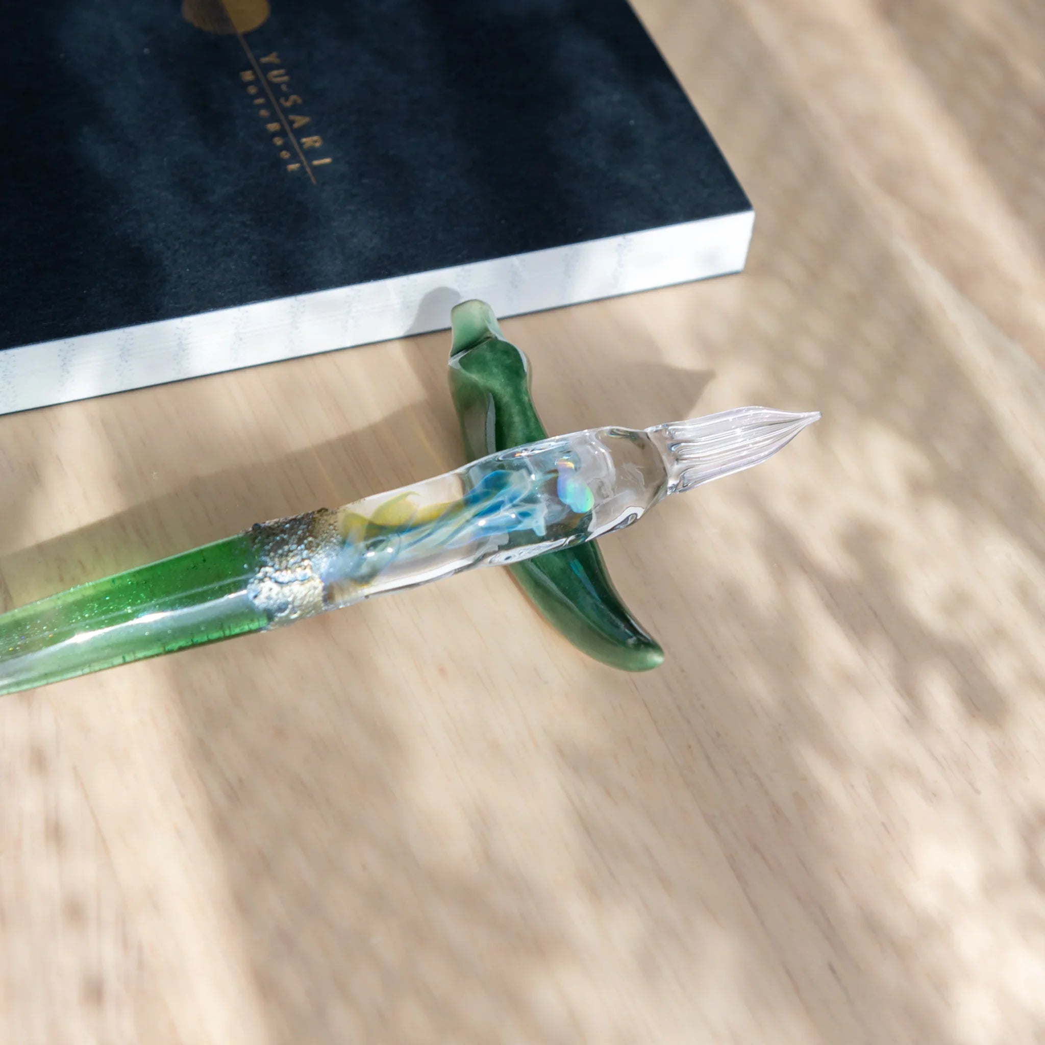 Three-tier ceramic dango pen rests in brown, white and mauve colors stacked on wooden dowel with support base detail