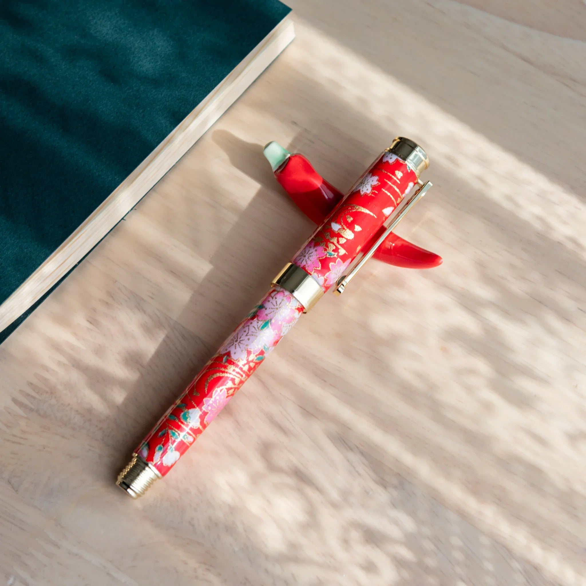 Flat lay photograph of pepper pen rest collection alongside dark fountain pen with botanical pattern accents nib