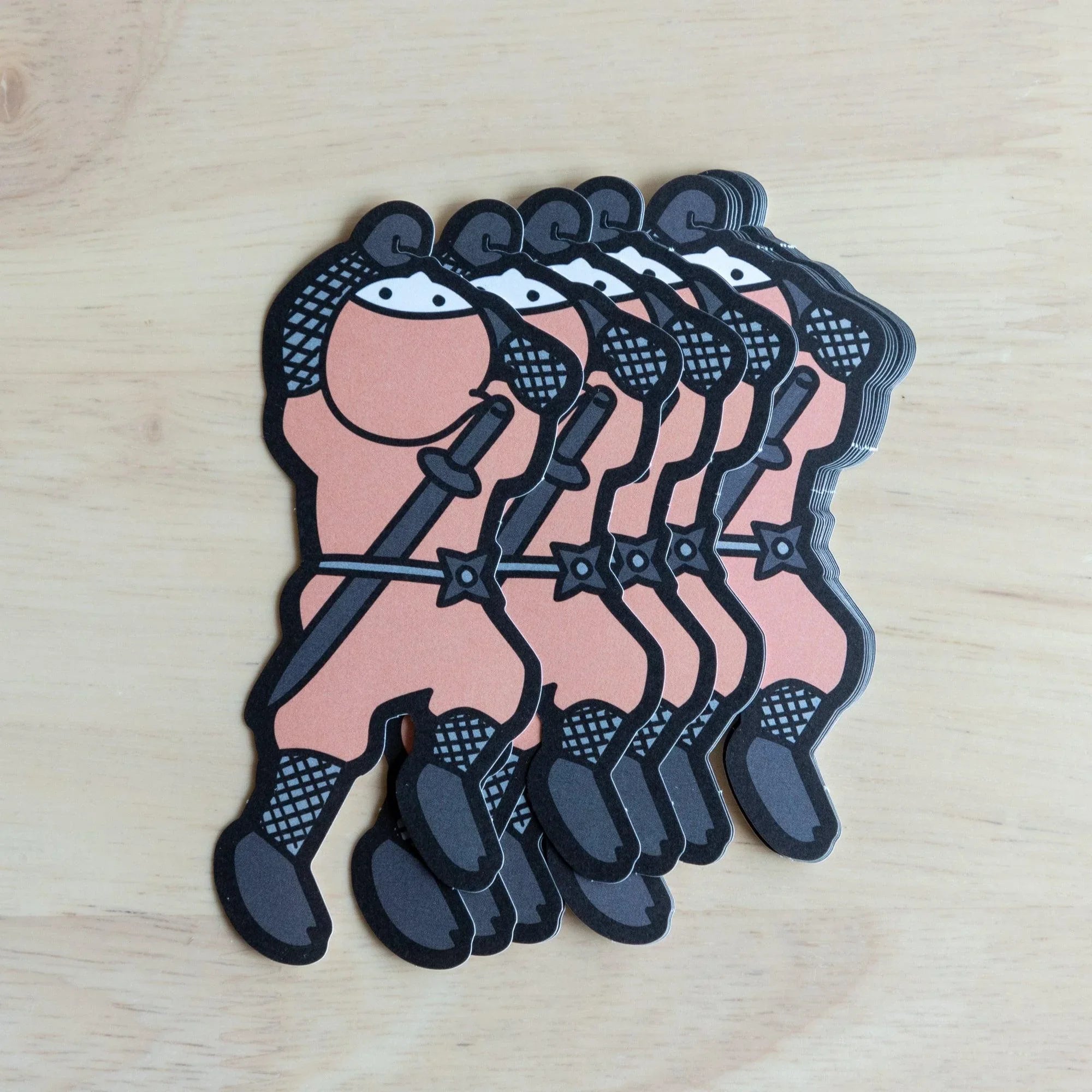 Stack of pink Shinobi-nsen ninja die-cut message cards fanned on wood, showing the pink ninja figure with katana and shuriken