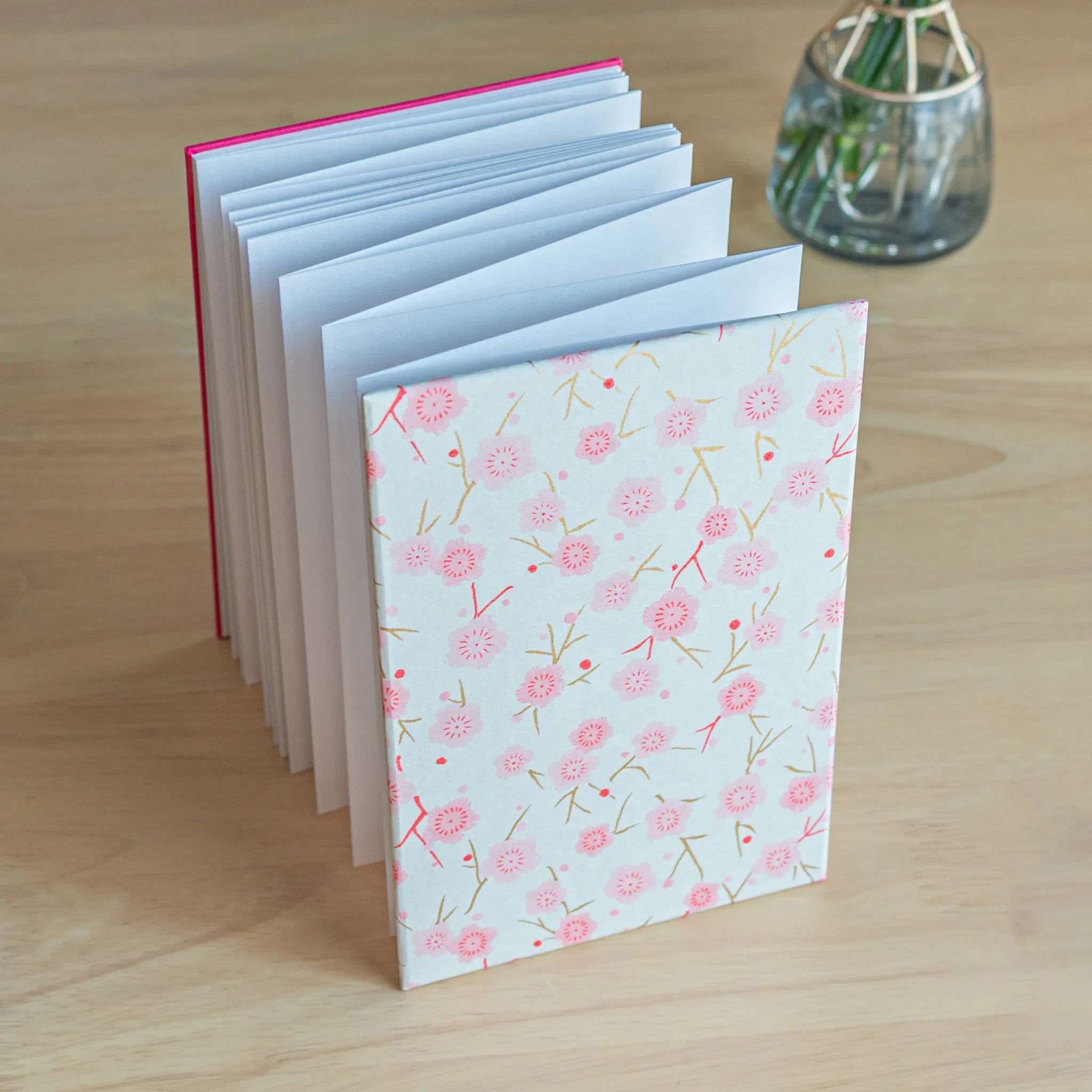 Pink Plum Blossoms washi goshuincho stamp book standing upright with accordion fold pages visible and hot pink binding spine