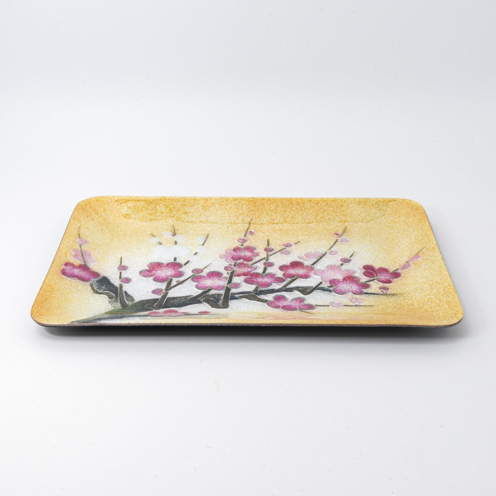 A side view of a golden tray adorned with vibrant plum blossom branches, emphasizing its textured surface and elegant motif.