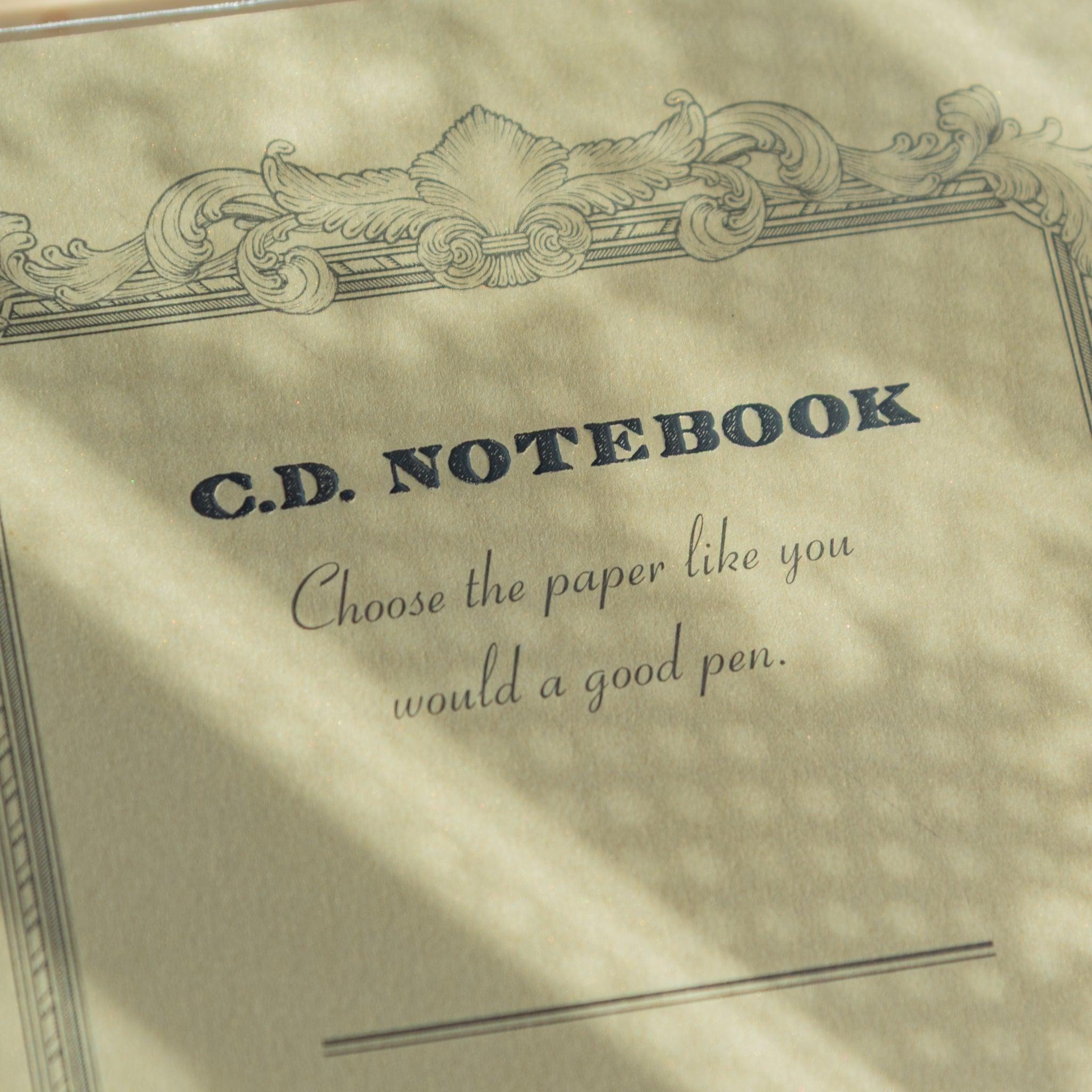 Close-up of gold cover Premium C.D. Japanese notebook with ornate border and fountain pen quote, reflecting elegant stationery