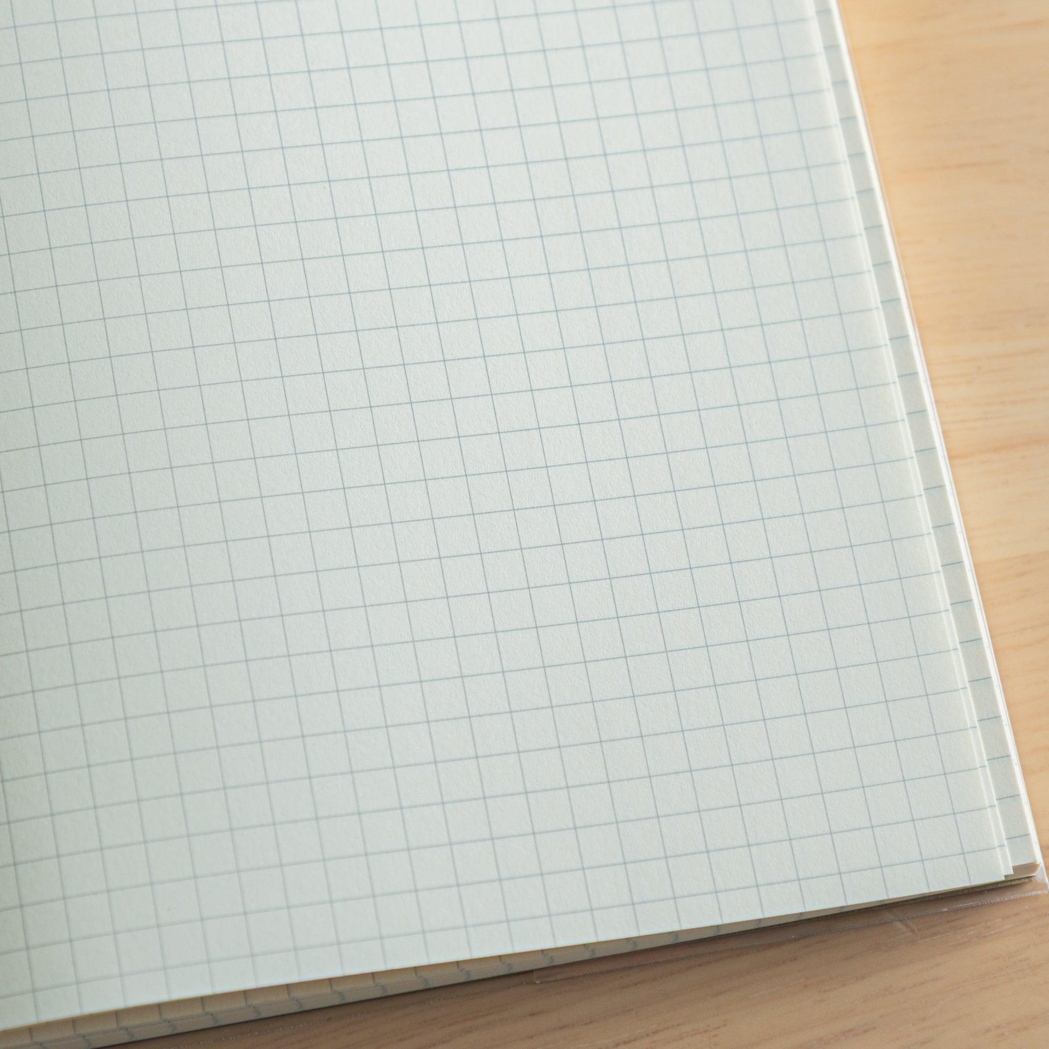 Close-up of grid paper in a Japanese notebook, showing smooth cream texture designed for fountain pen-friendly writing.