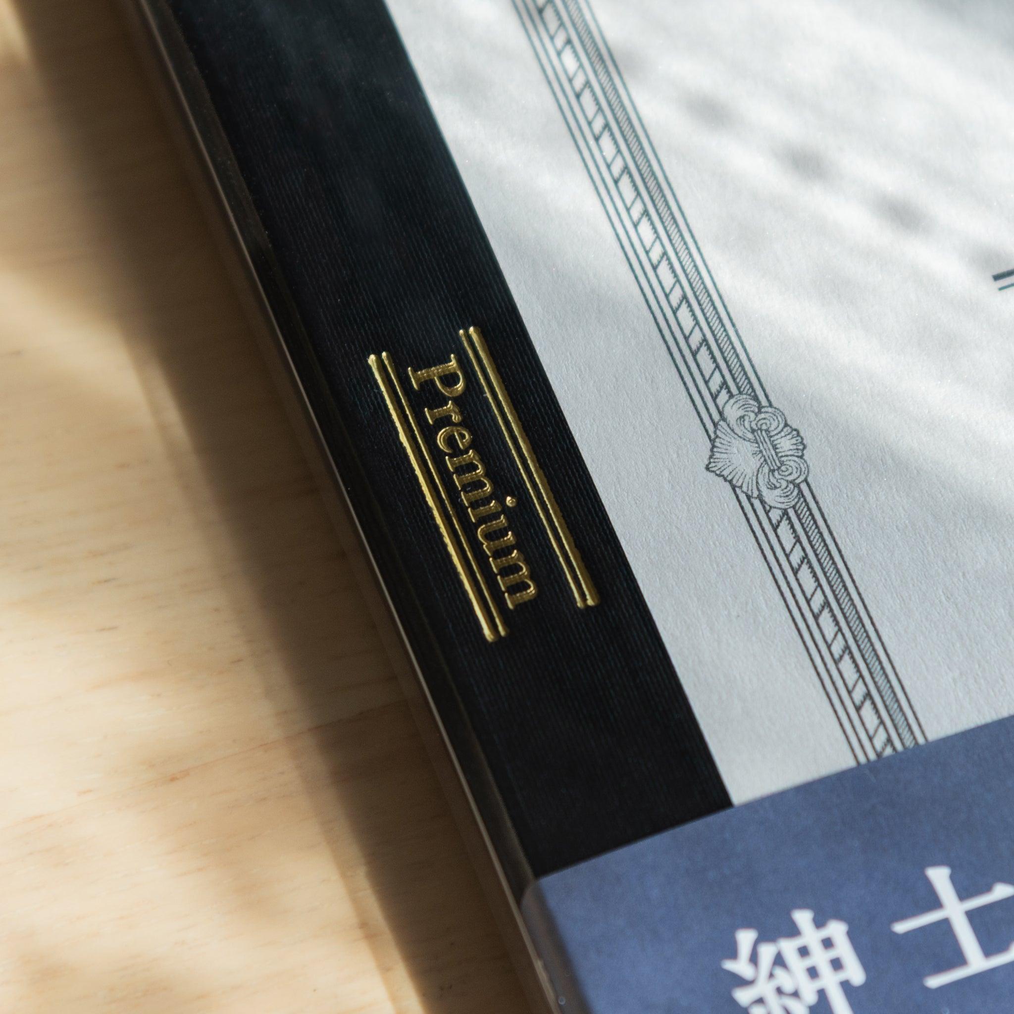 Macro shot of the Premium gold foil label on a Japanese notebook spine, part of the high-end Japanese stationery collection