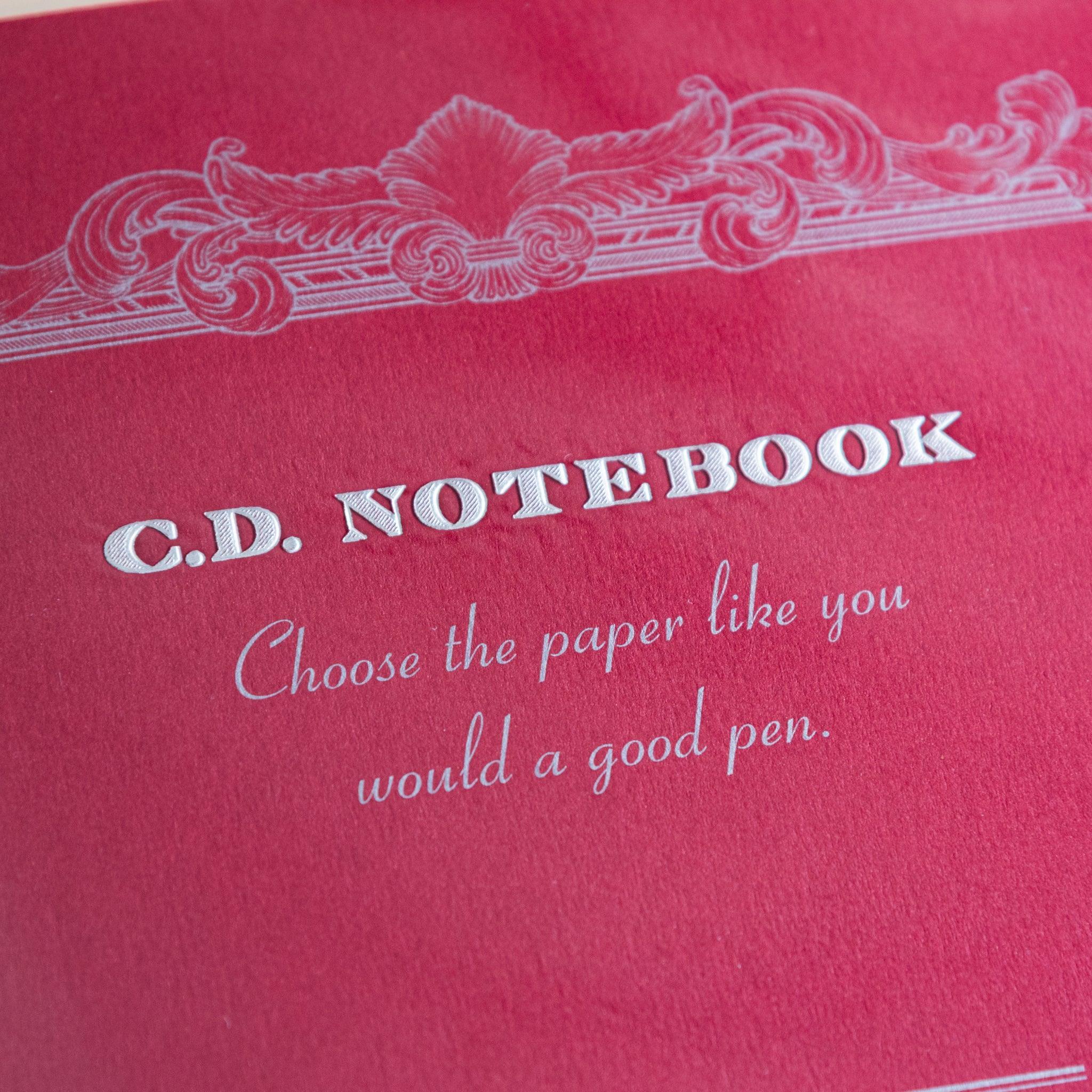 Close-up of red Premium CD Japanese notebook cover with elegant border and quote about quality paper for a good pen.