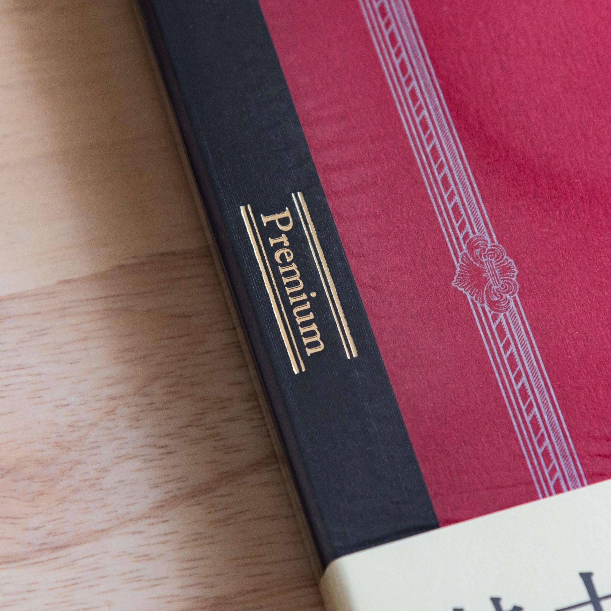 Gold foil "Premium" label on the spine of a red Japanese notebook, part of the refined and high-end CD NOTEBOOK series