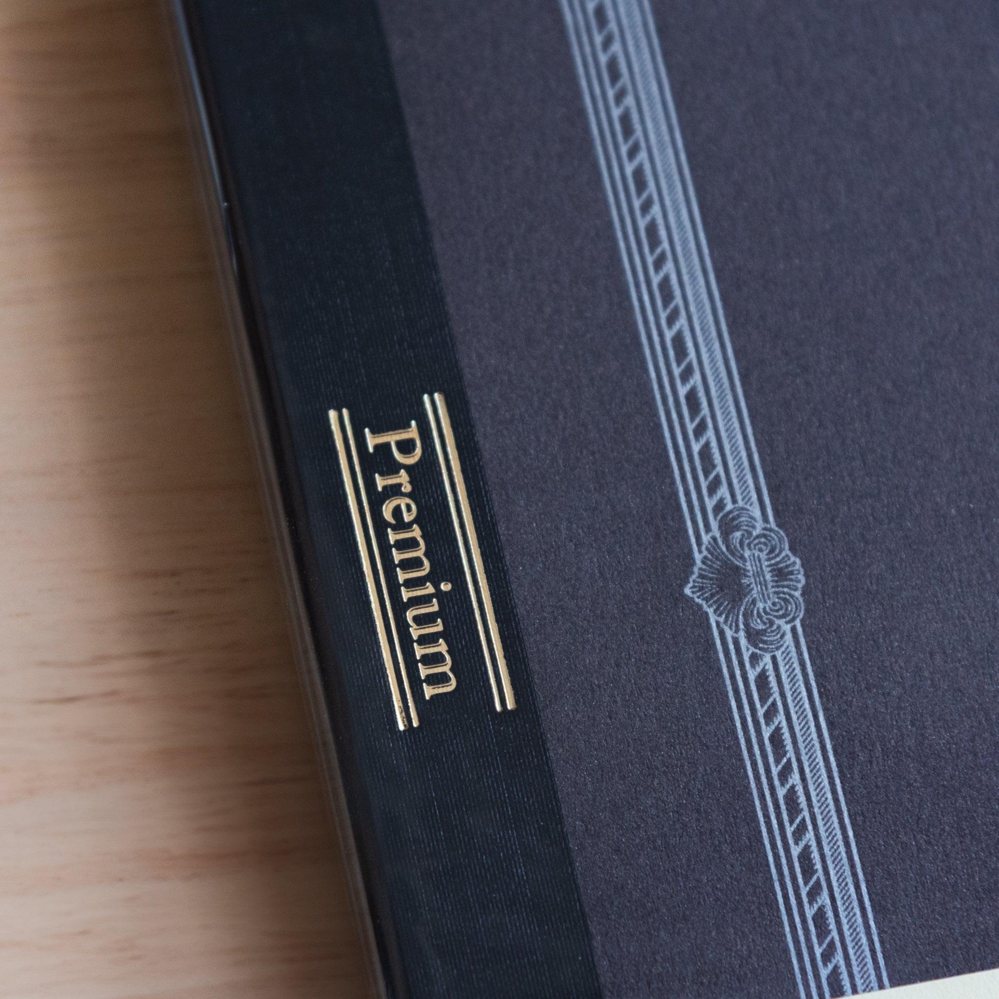 Gold foil "Premium" label on the spine of a black Japanese notebook, part of the refined and high-end CD NOTEBOOK series
