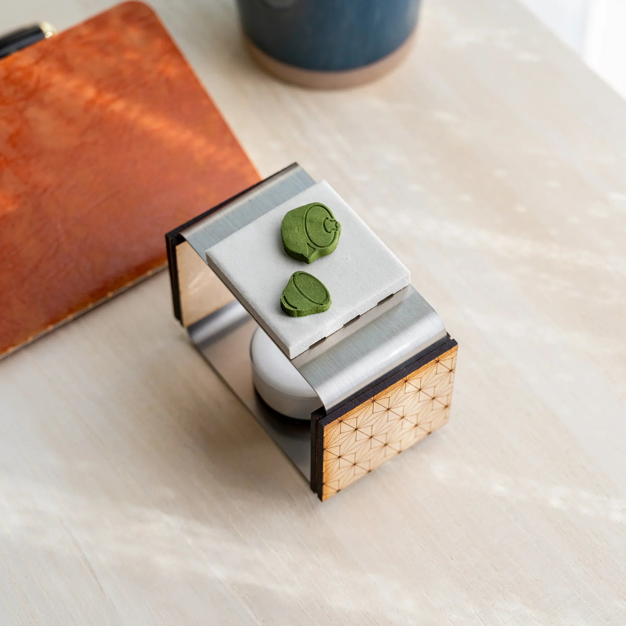 Foldable matcha incense tea warmer with asanoha wood and a teapot-shape pressed matcha piece on the ceramic plate