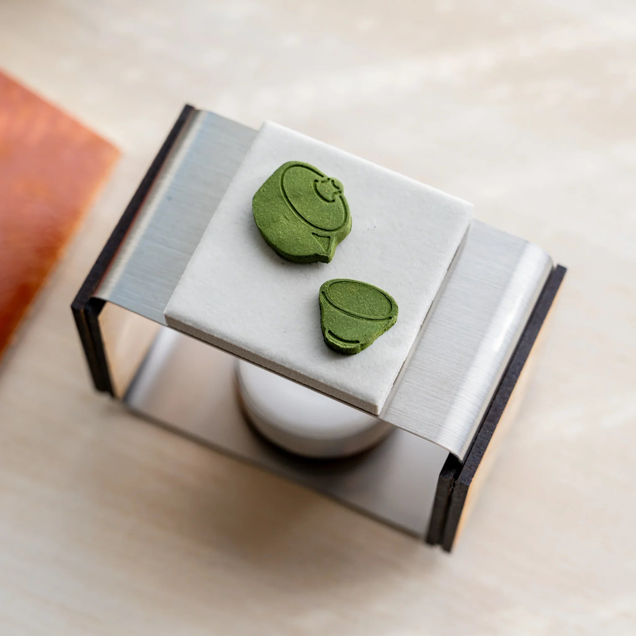Close-up of teapot and tea cup pressed matcha incense pieces on the ceramic plate of foldable matcha incense tea warmer