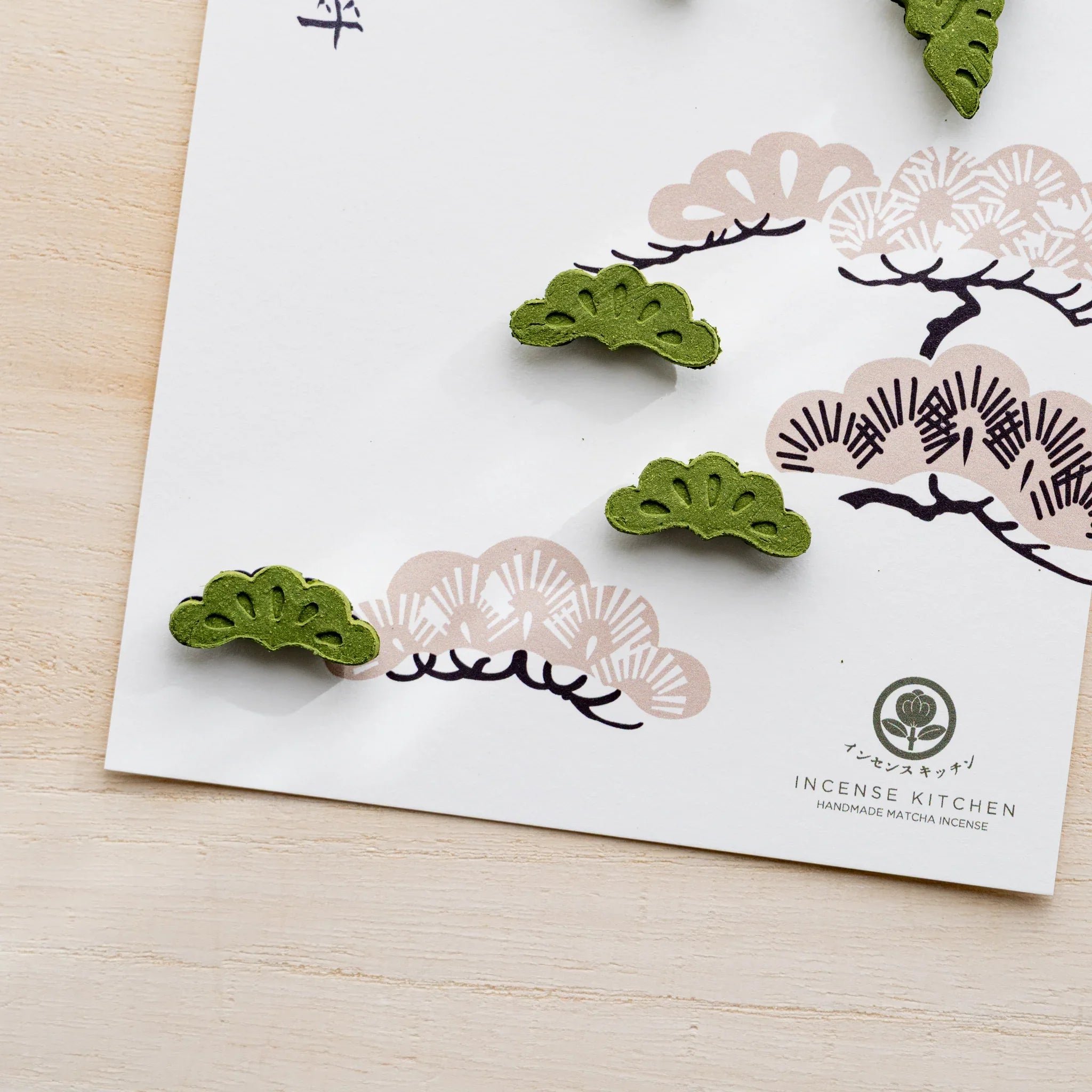 Close-up of pine variant pressed matcha incense card with green pine-sprig pressed pieces and INCENSE KITCHEN logo