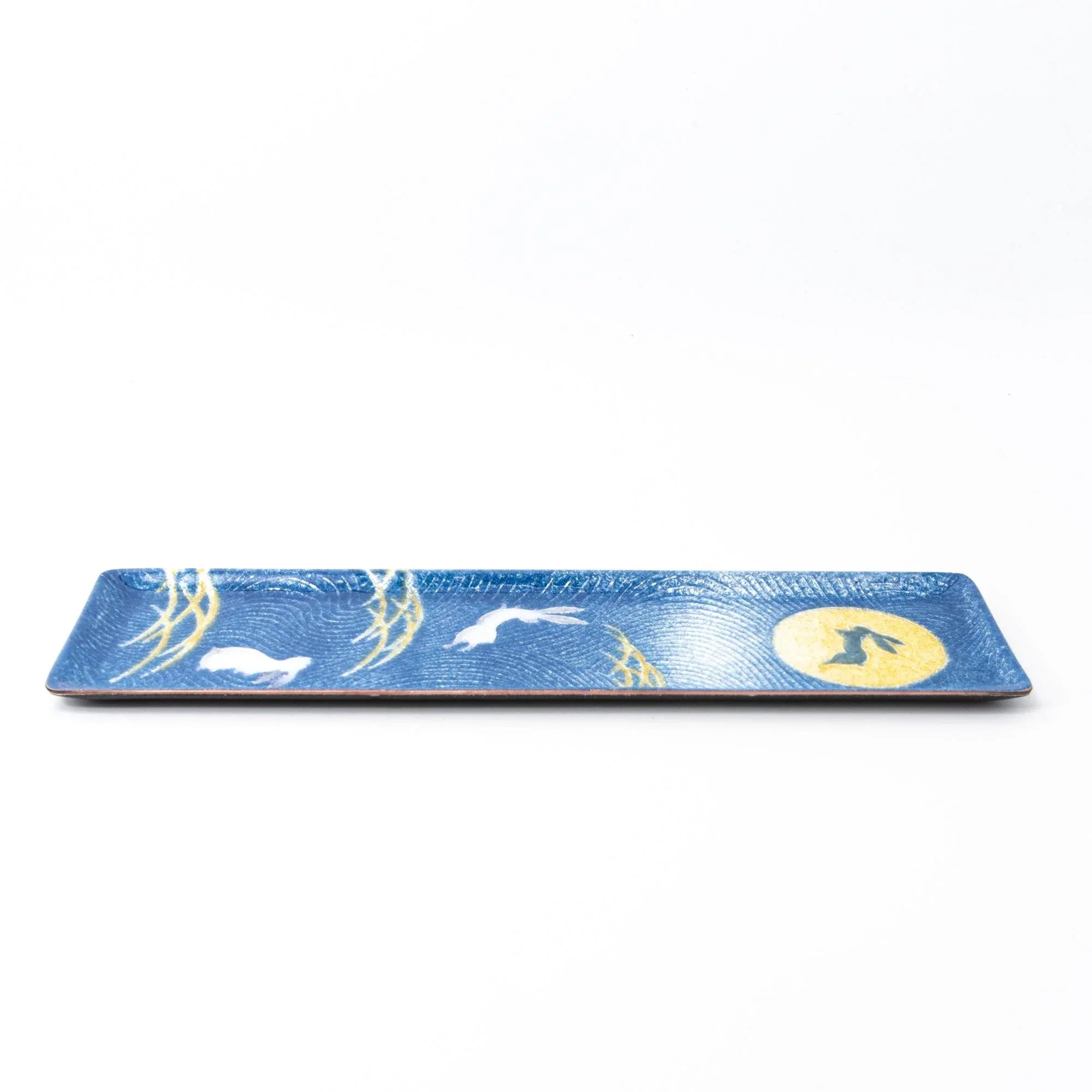 Dark blue enamel slim pen tray, side view on white background, showing white rabbit, gold pampas grass, and gold moon