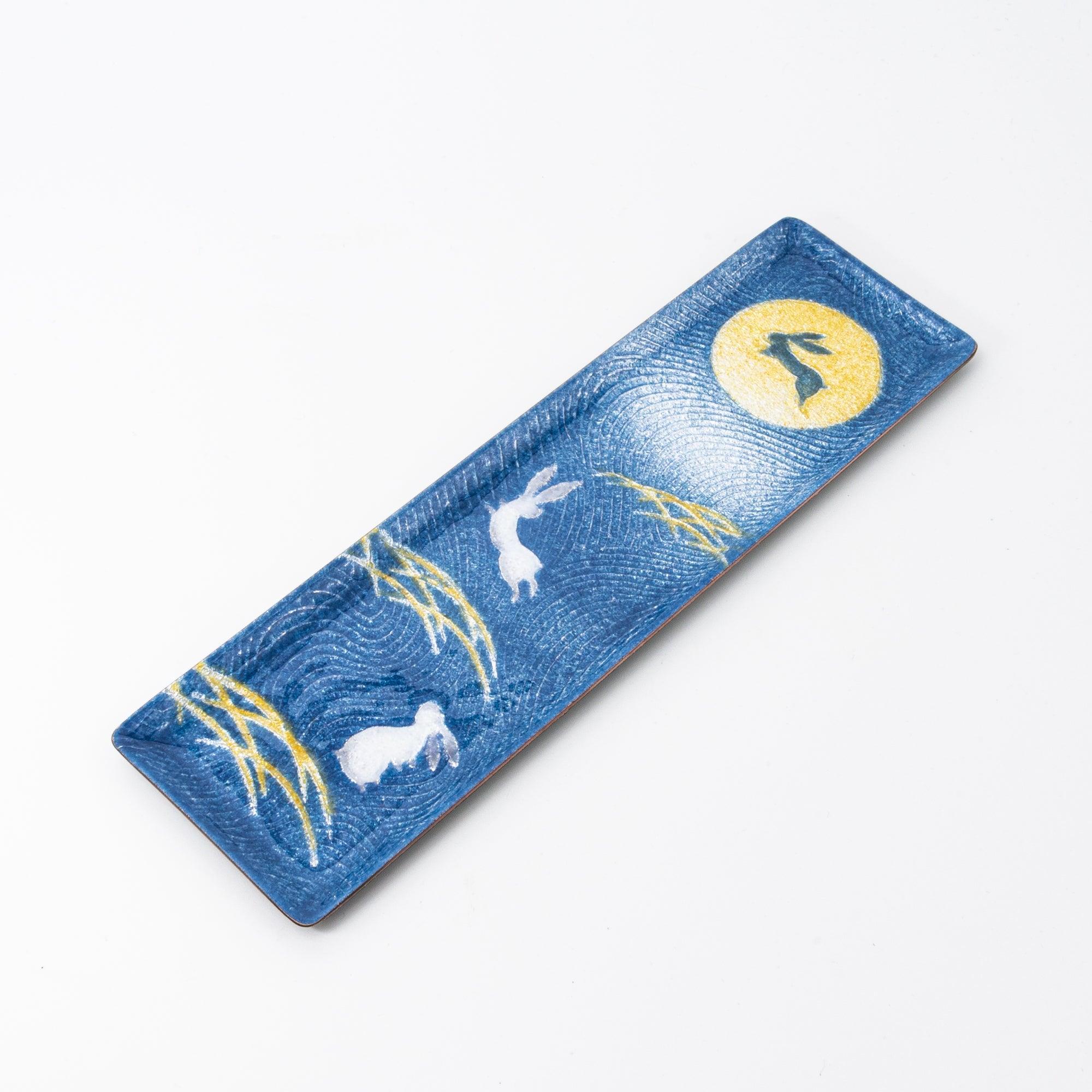 Dark blue enamel slim pen tray on white background, angled view, full design: gold moon, white rabbits, and gold pampas grass