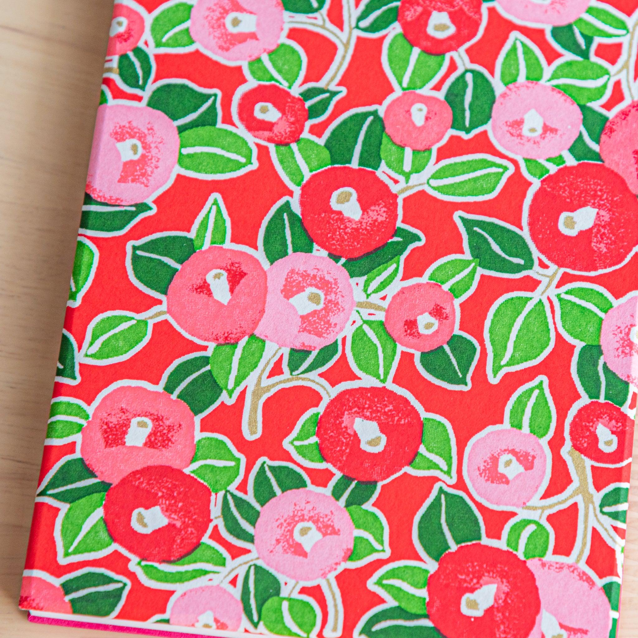 Close-up of red camellia-patterned Goshuinsho stamp book cover, showcasing traditional Japanese washi design.