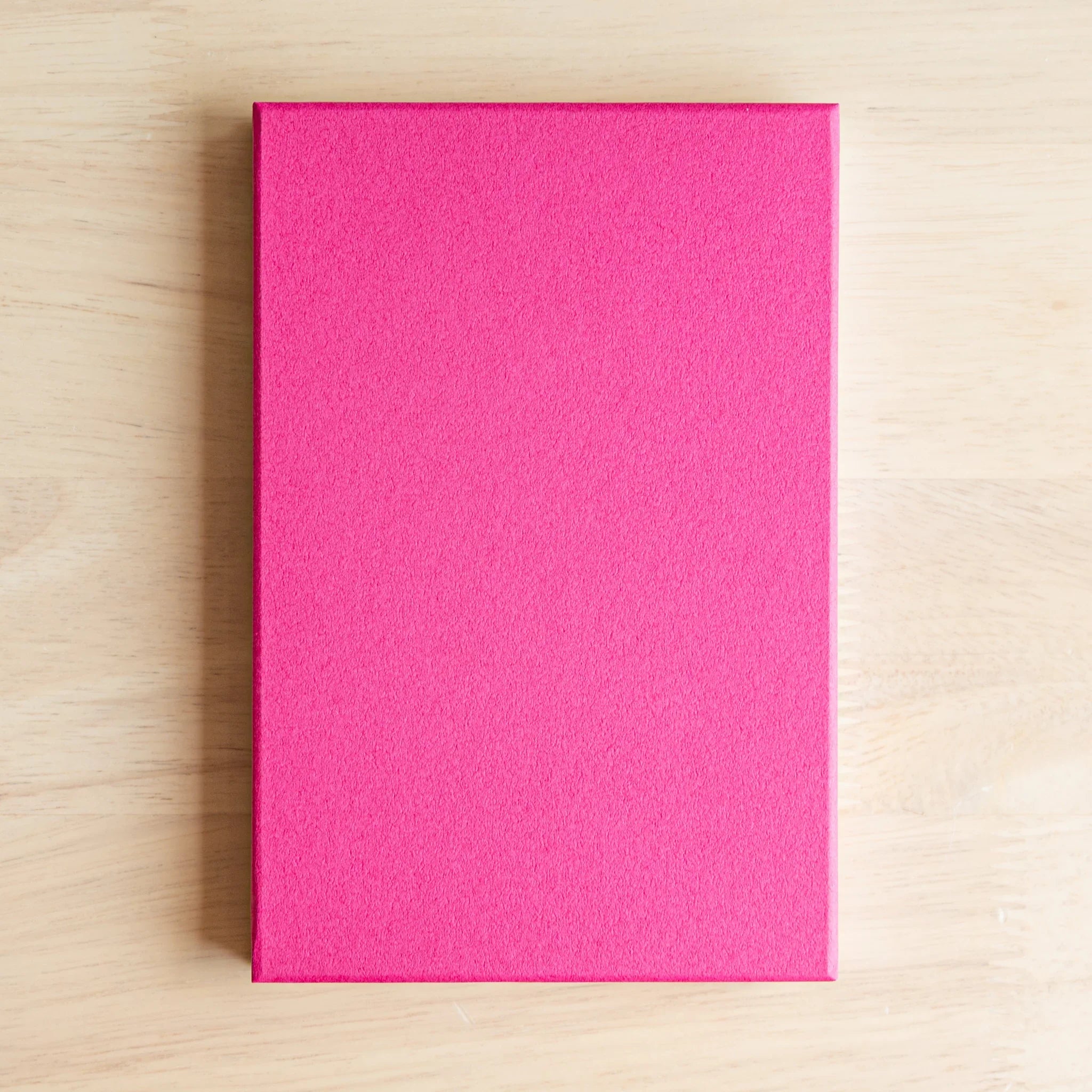 Red Camellia washi goshuincho back cover showing solid hot pink textured surface on light wood