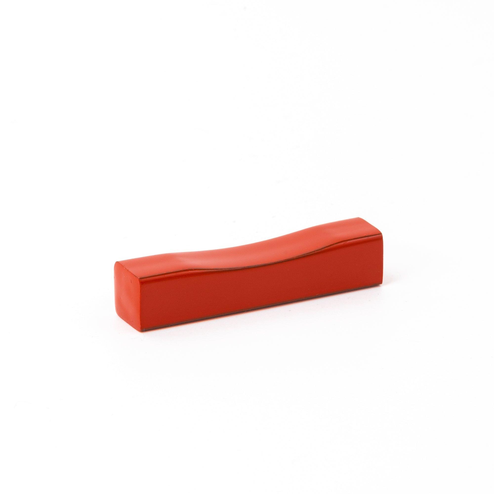 A red lacquered pen rest, a piece of Japanese stationery with a minimalist and elegant design.