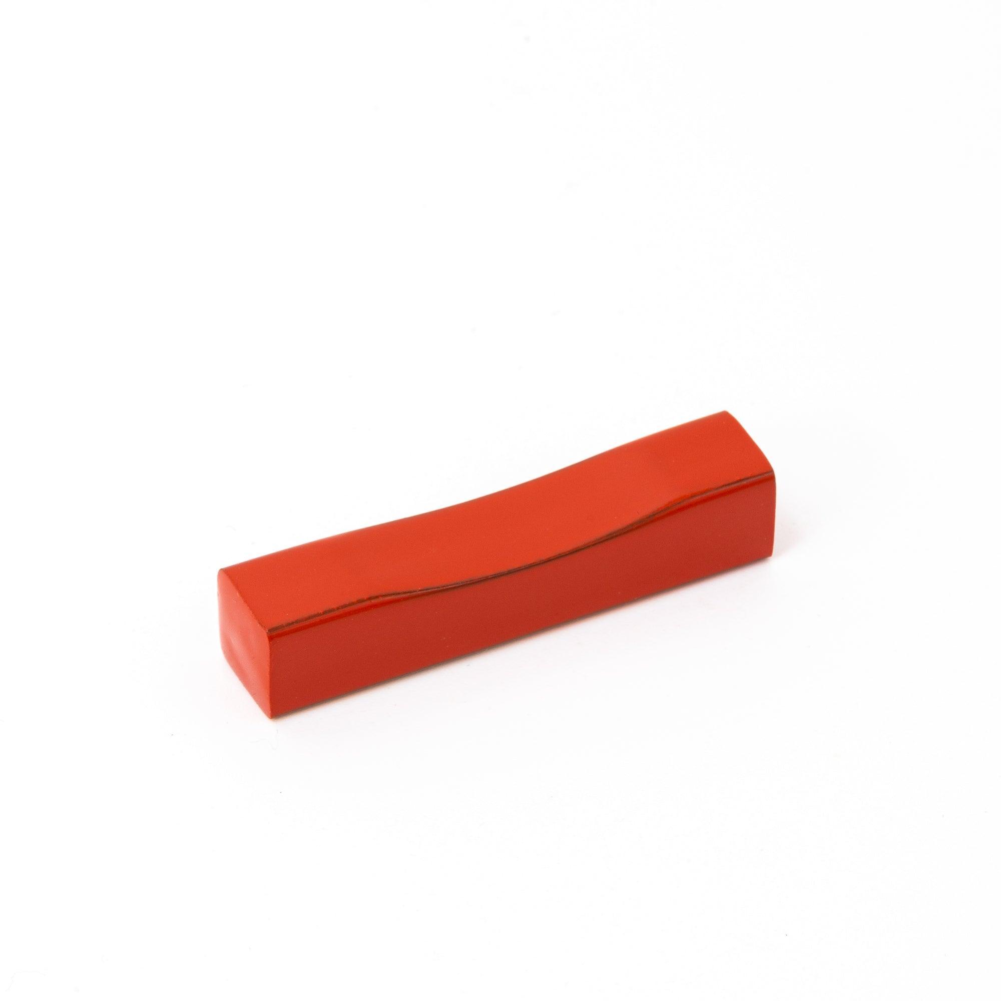 A red lacquered pen rest, a piece of Japanese stationery with a minimalist and elegant design.