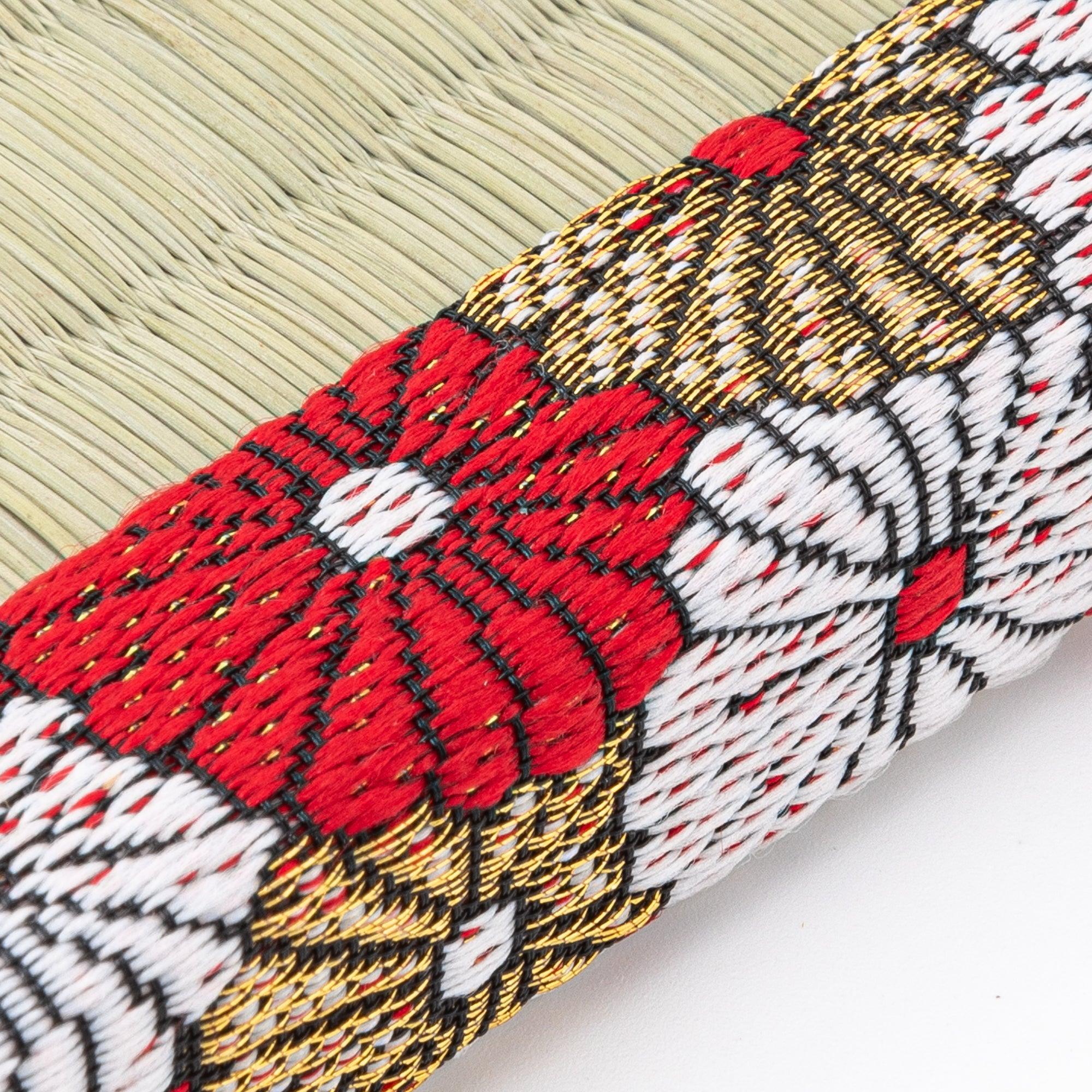 Extreme close-up of chrysanthemum embroidery on Japanese tatami pen tray brocade border showing red, white, and gold thread
