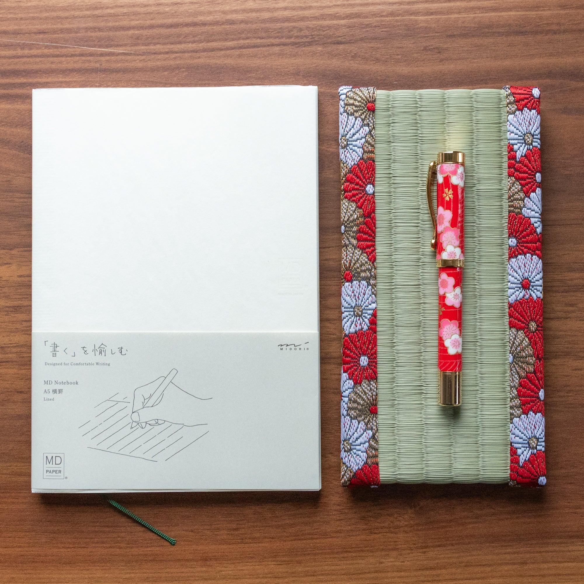 Japanese tatami pen tray with chrysanthemum brocade border holding a red floral fountain pen beside MD A5 lined notebook