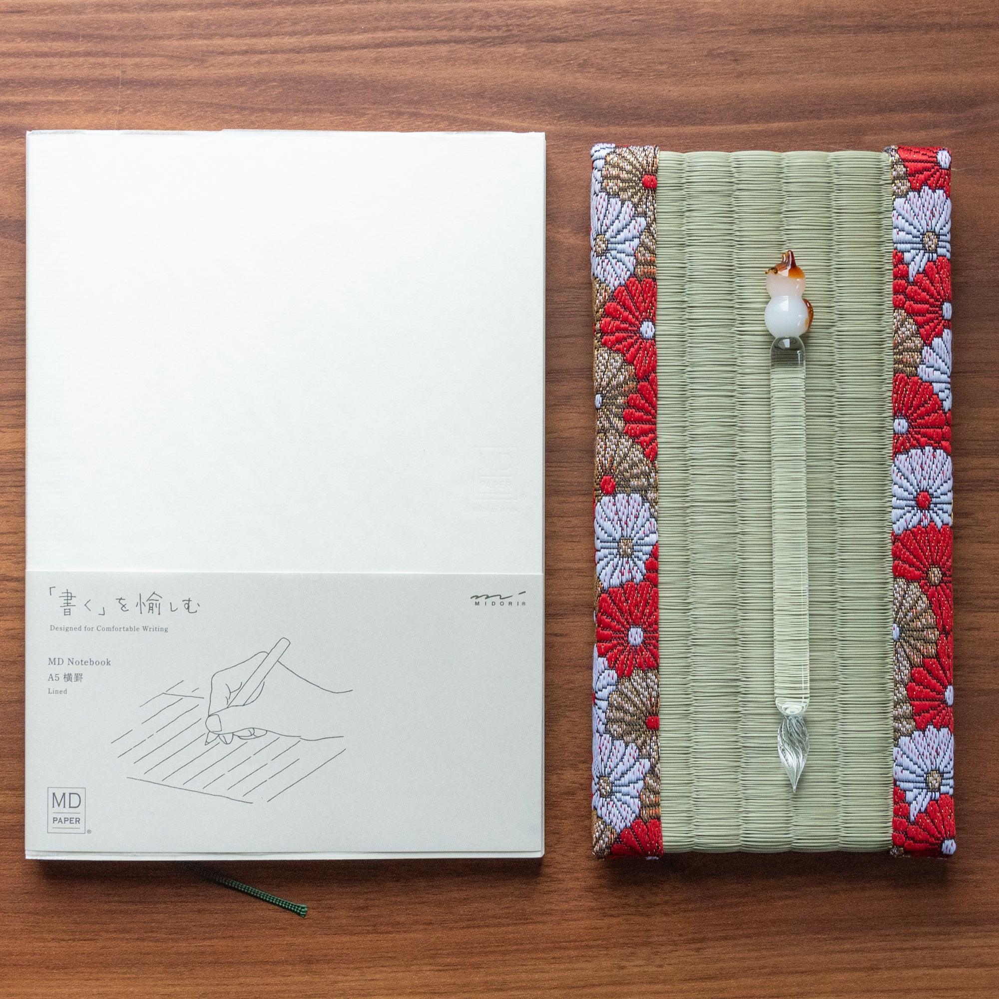 Japanese tatami pen tray with chrysanthemum brocade border holding a cat figurine glass dip pen beside MD A5 lined notebook