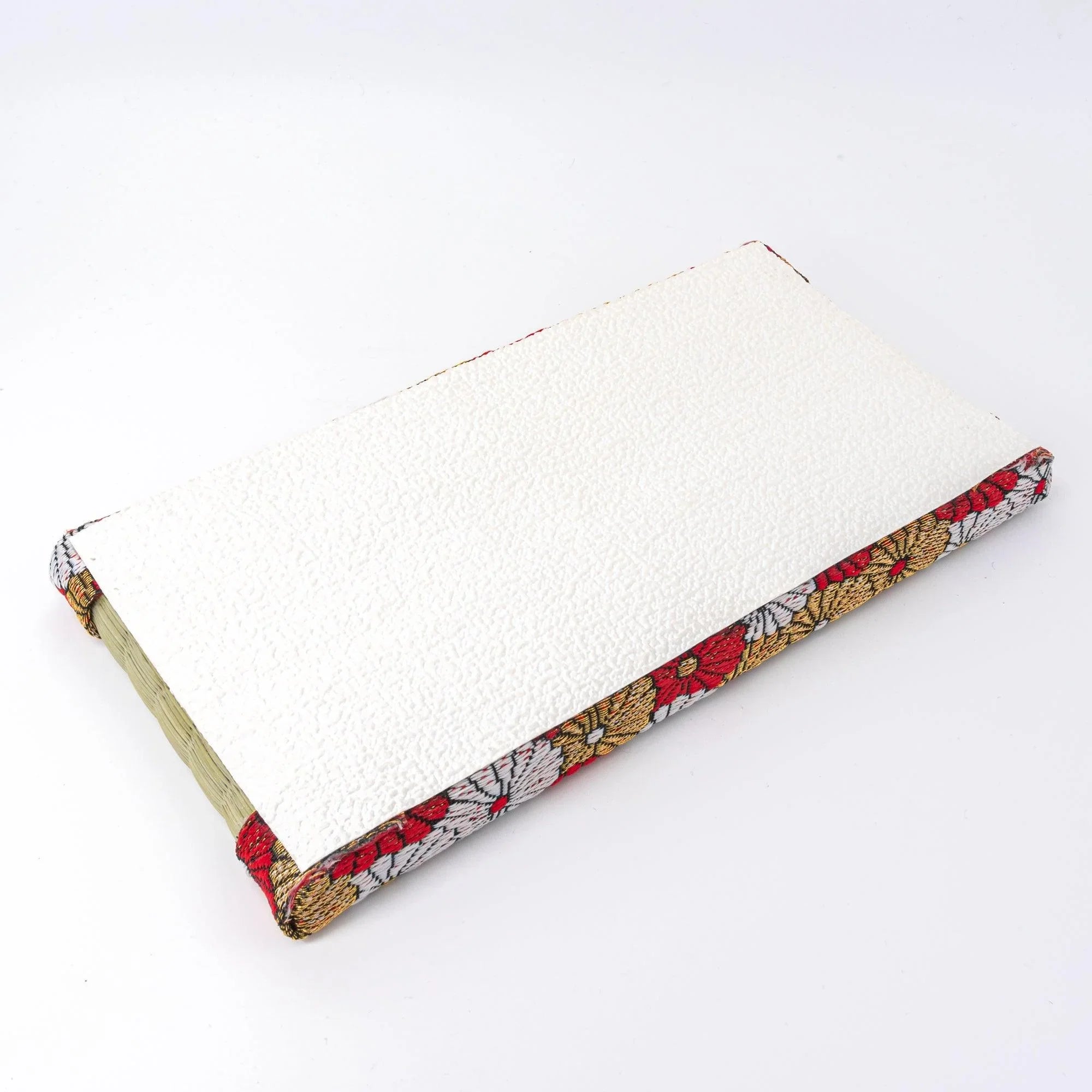 Japanese tatami pen tray turned upside down showing white textured leatherette base with chrysanthemum brocade border edges