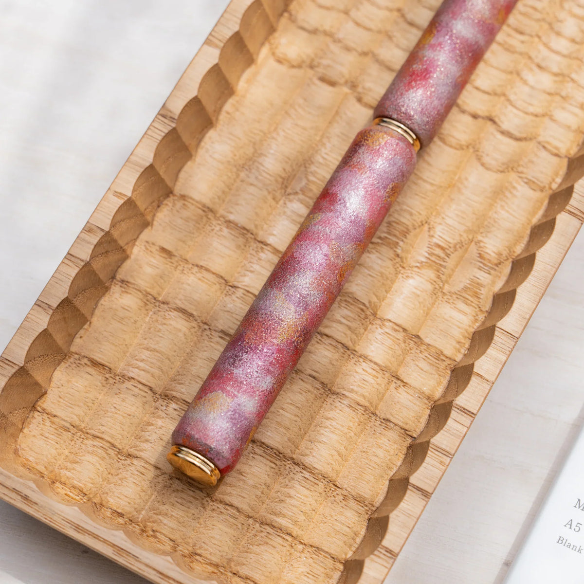 Close-up of the marbled color urushi surface on the red zelkova wood rollerball pen
