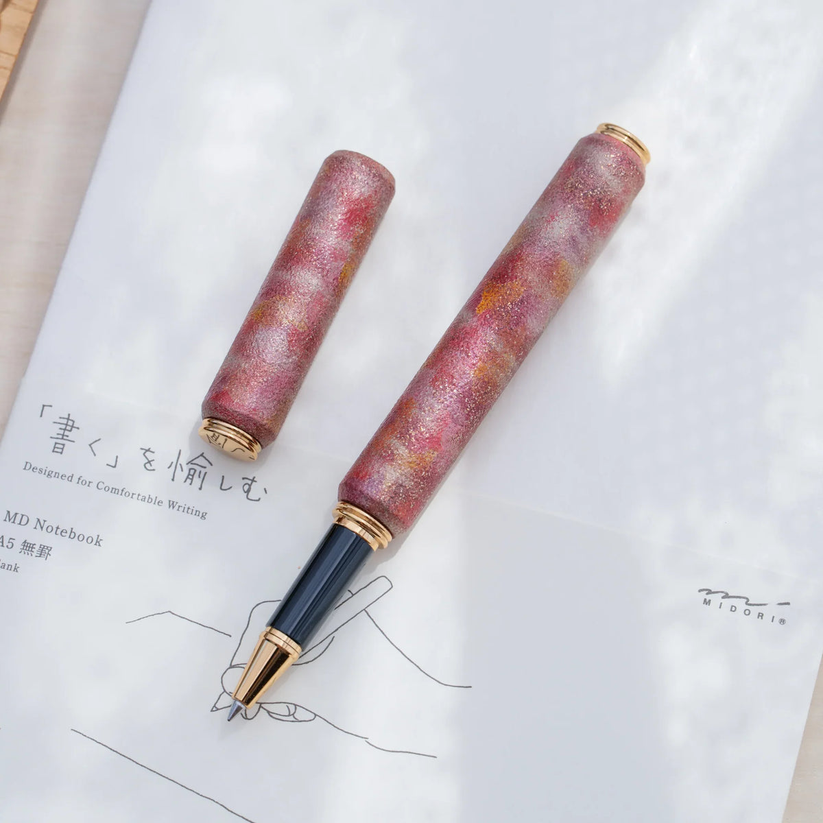 Gold trimmed rollerball tip of the red marbled urushi lacquered rollerball pen