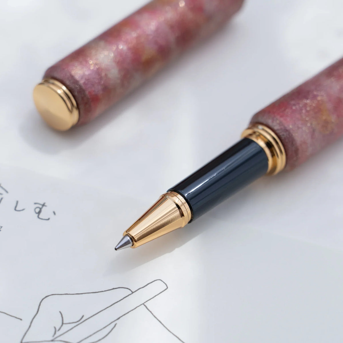 Gold trimmed rollerball tip of the red marbled urushi lacquered rollerball pen