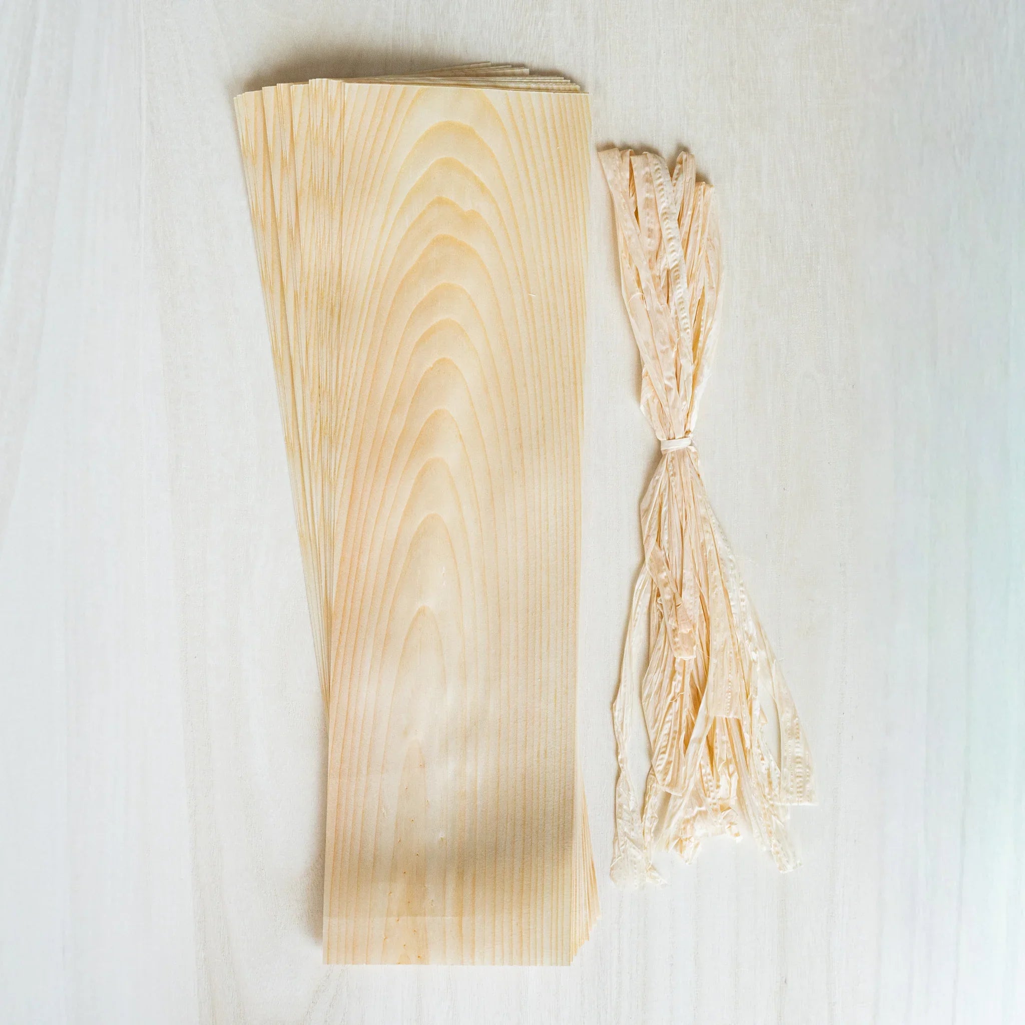Red Pine Wood Art and Craft Sheets stacked beside a tied bundle of Hinoki strings on a pale wood surface