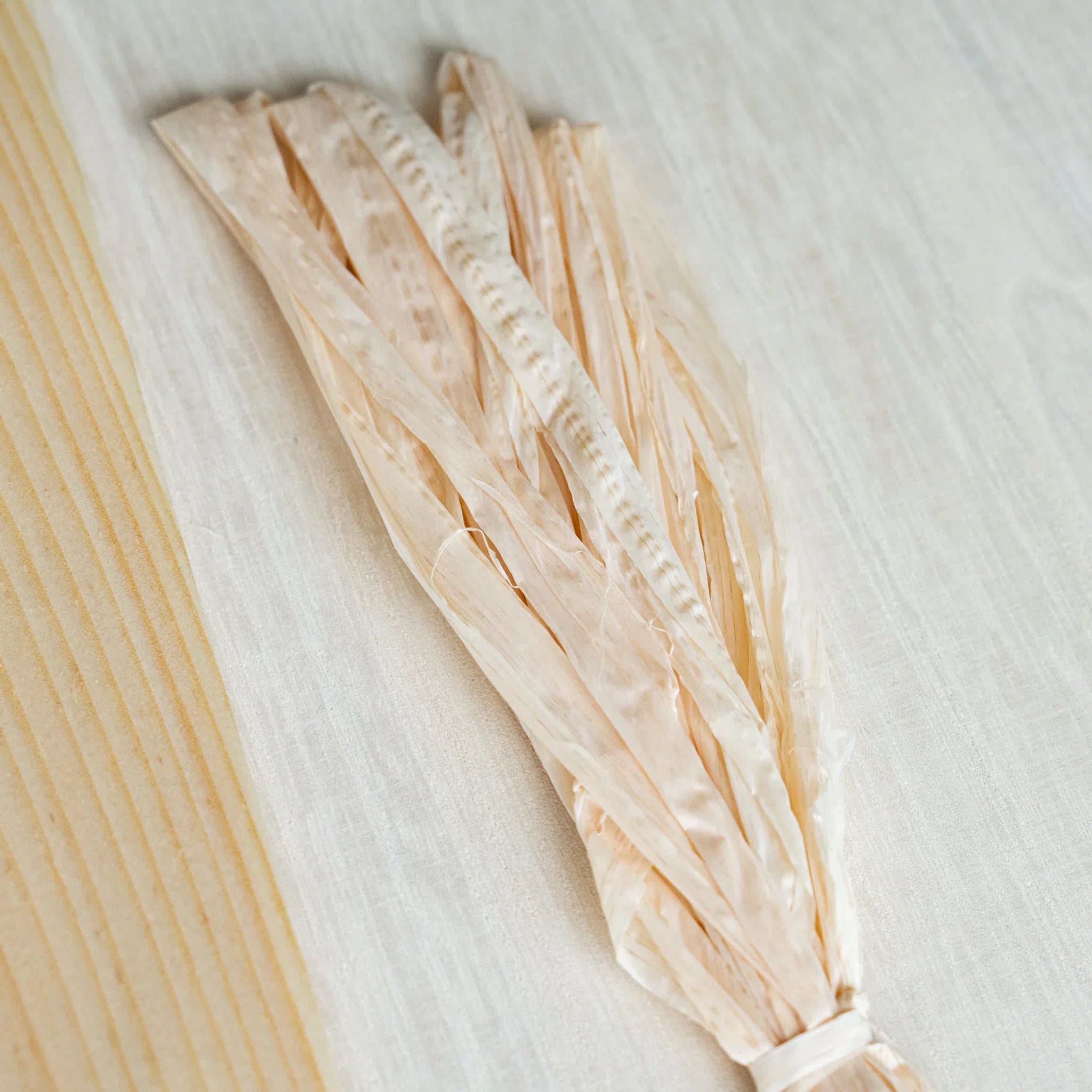 Tied bundle of Hinoki wood strings lying beside the grain edge of a Red Pine Wood Sheet